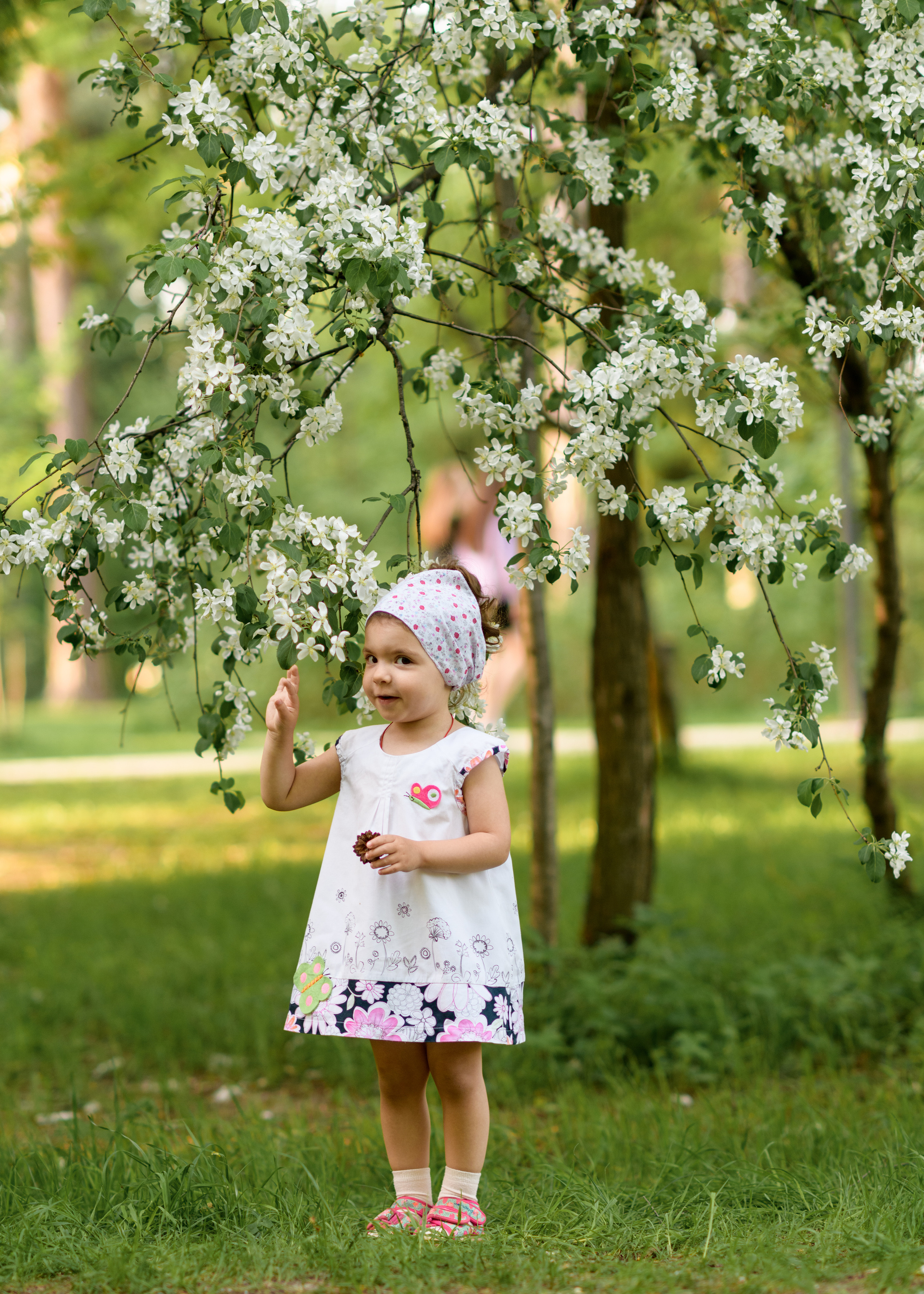 девочка в белом платье стоит у цветущей яблони