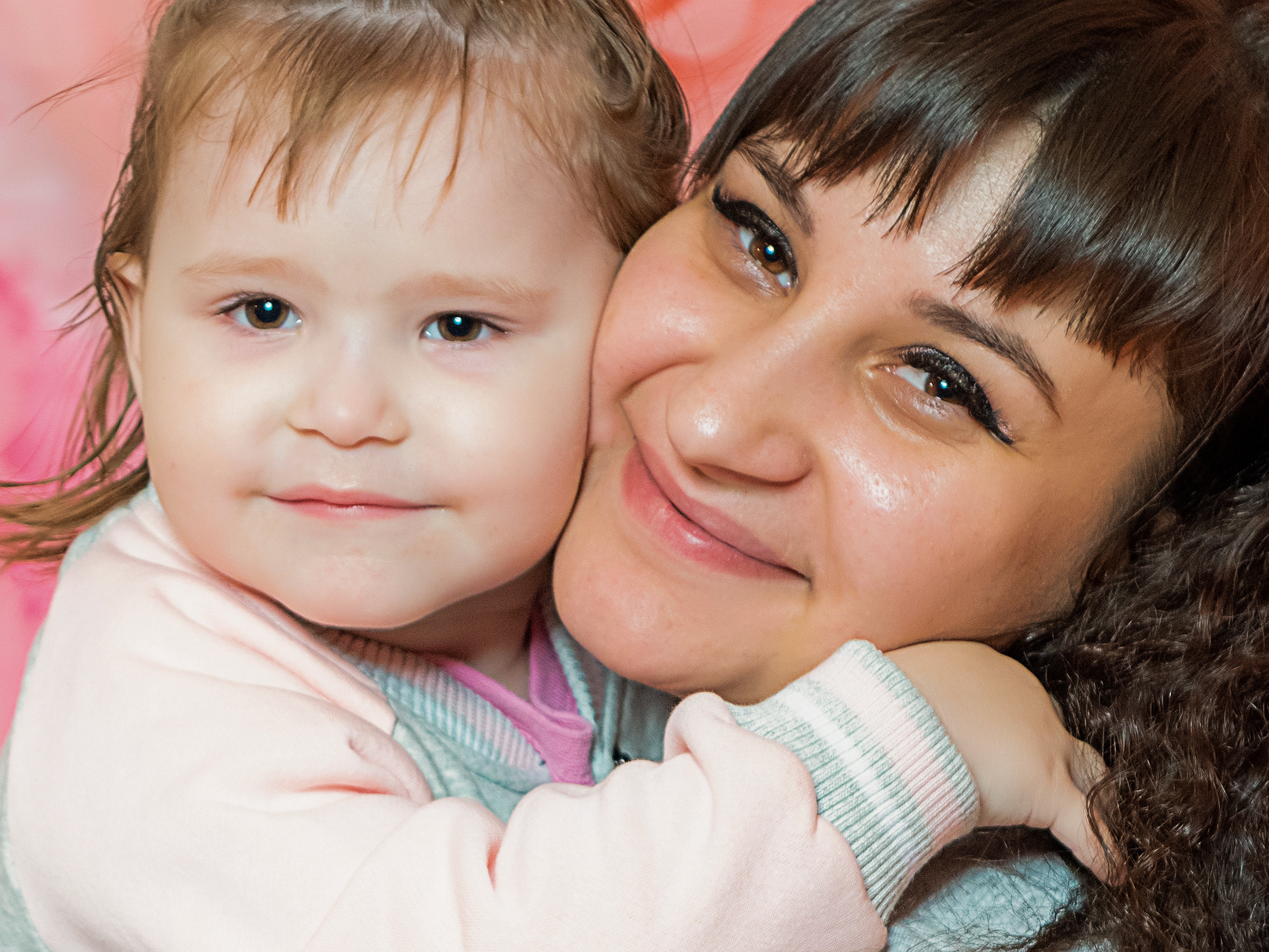 крупный портрет мамы с обнимающей ее дочкой улыбаются 