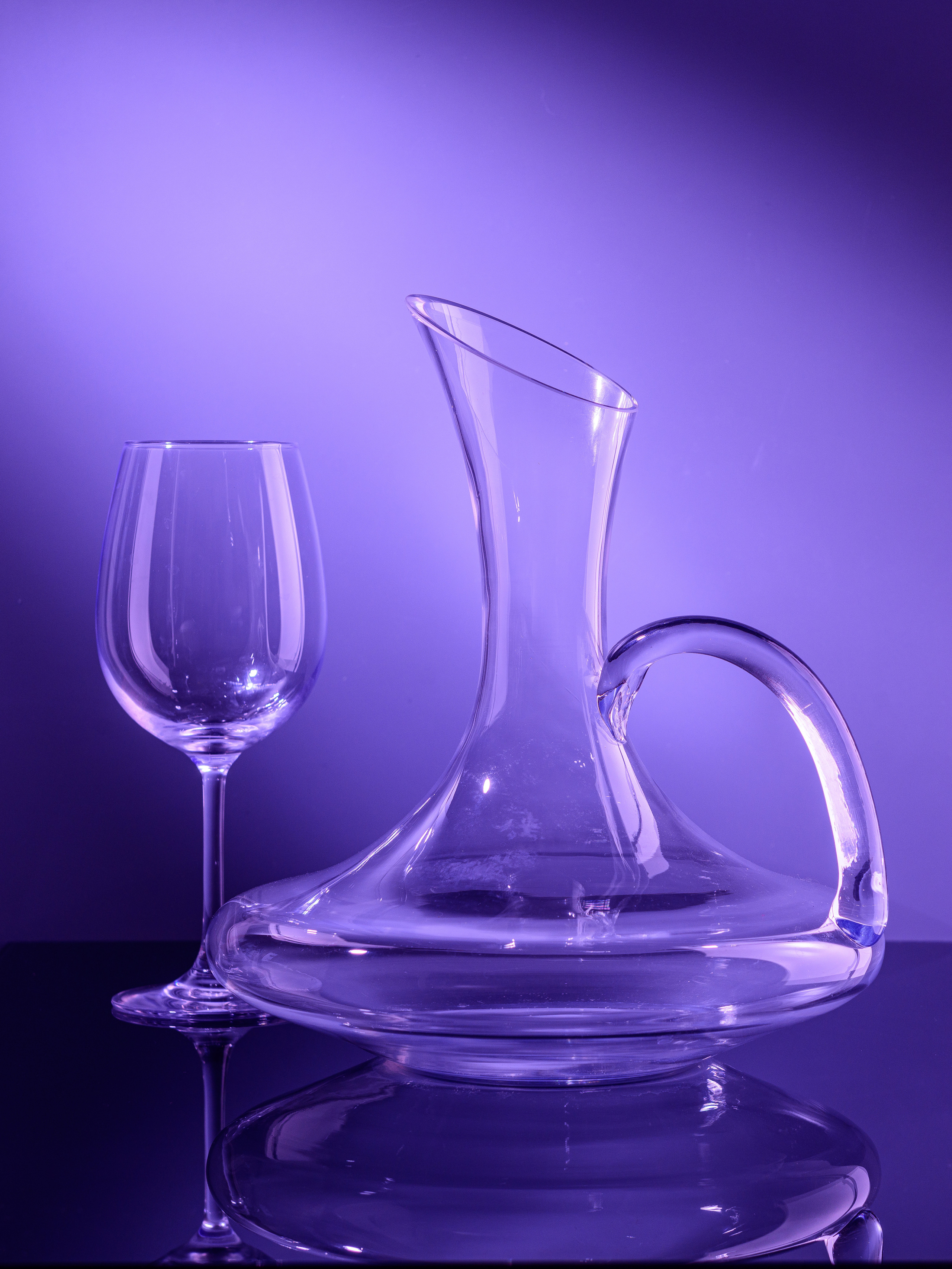 стеклянный графин в цветном освещении с бокалом и отражением