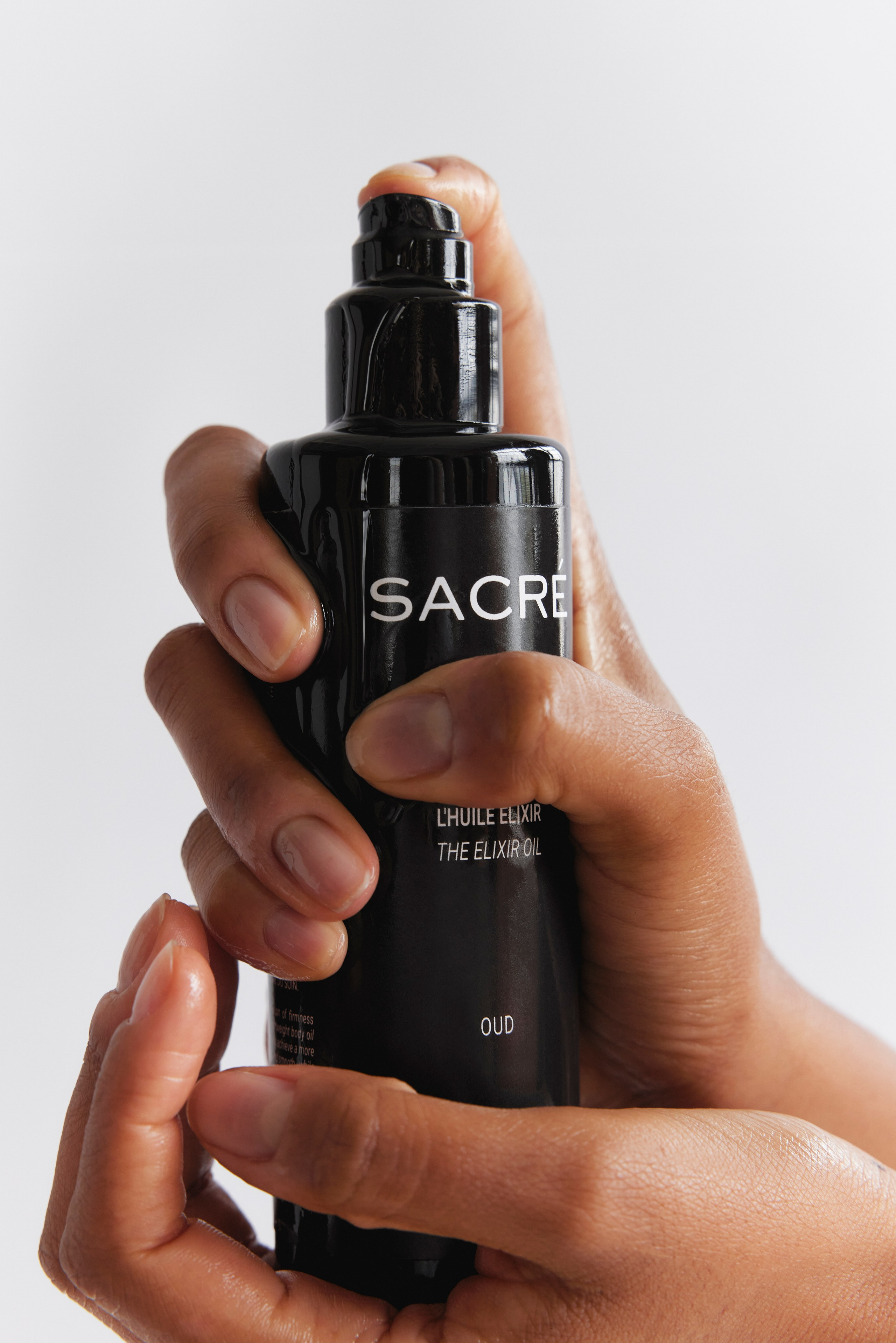 Close-up of a hand holding a serum bottle, highlighting premium skincare packaging design.