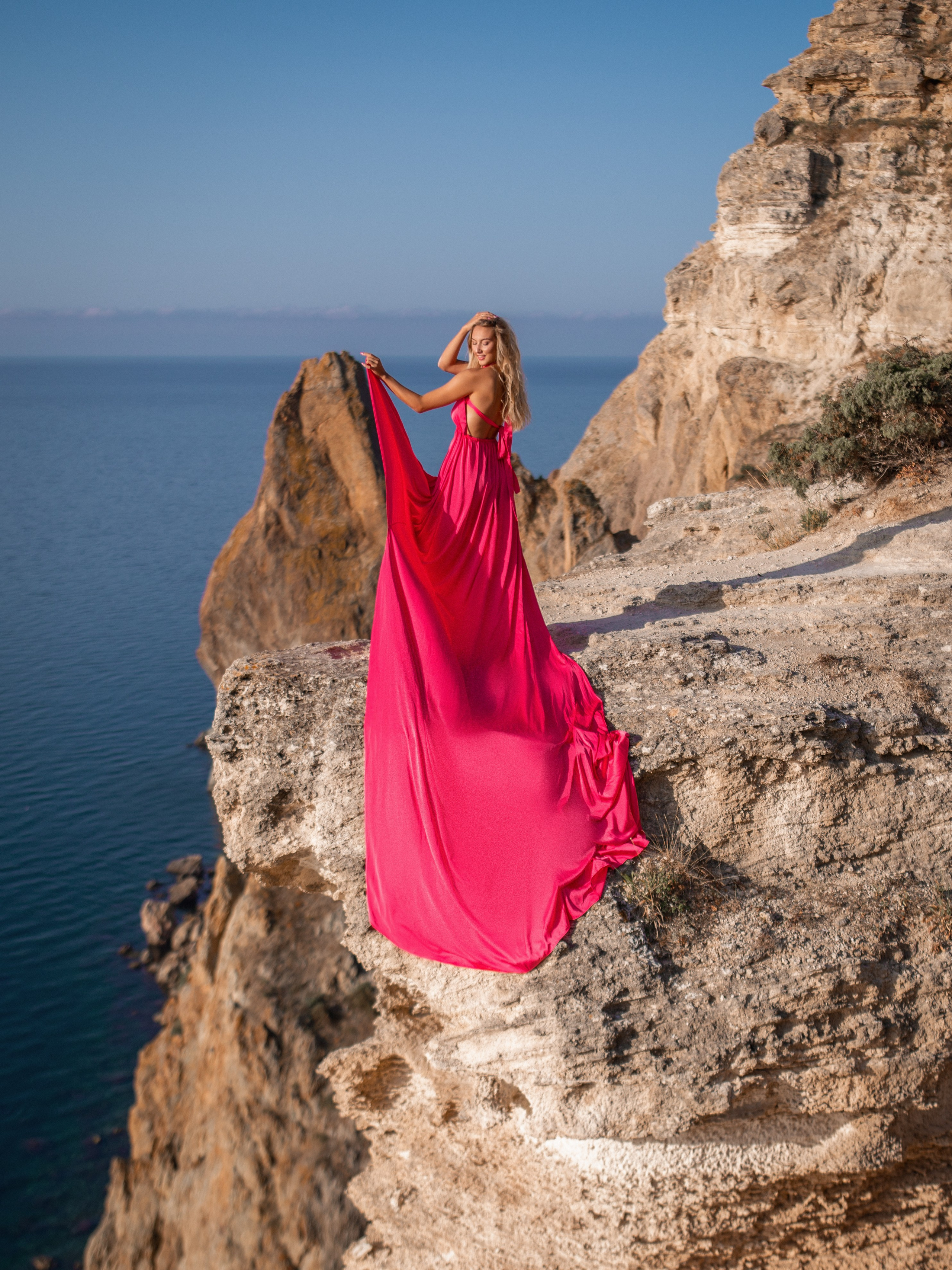 Девушка в платье розового цвета на скальном обрыве в Севастополе