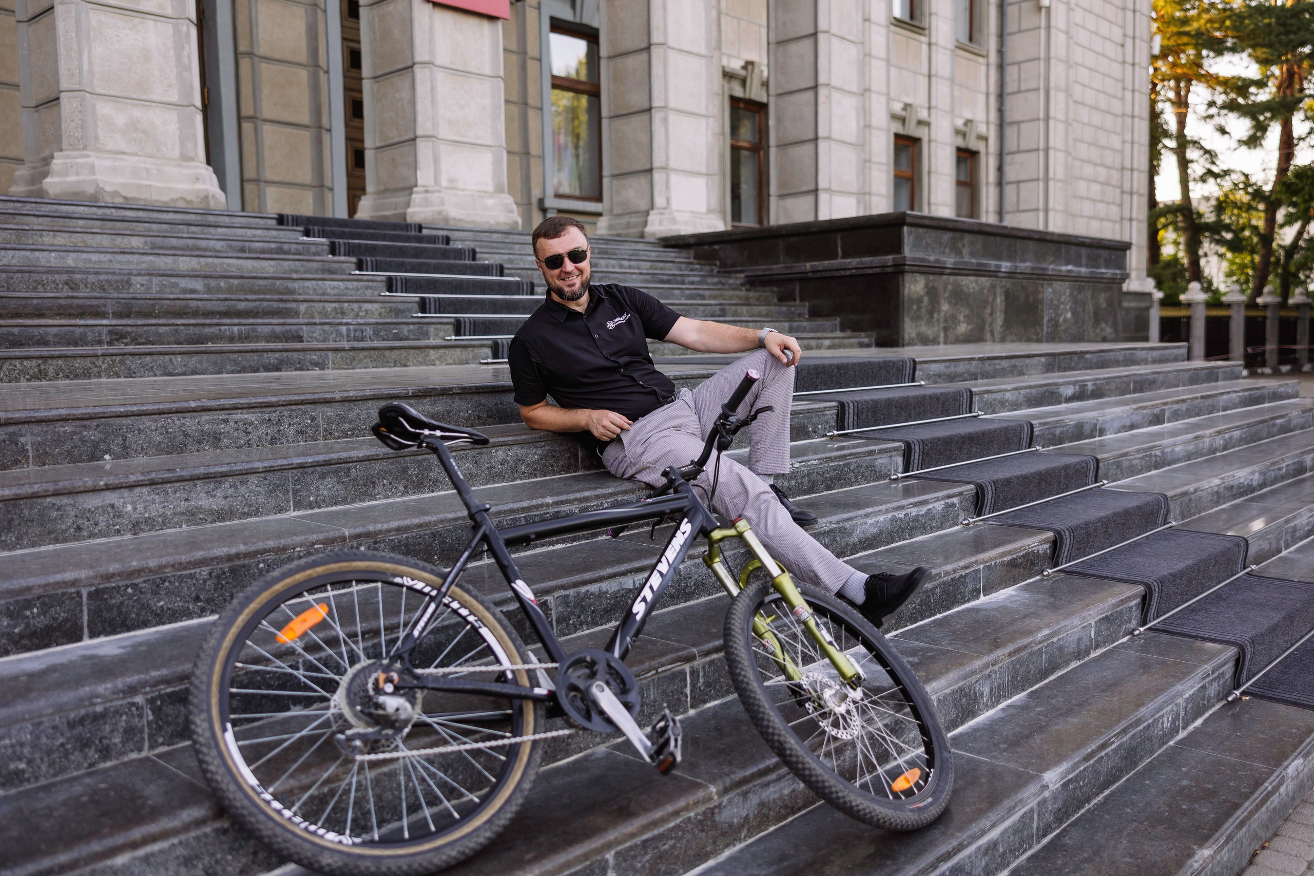 Мужчина сидит на ступеньках и позирует фотографу