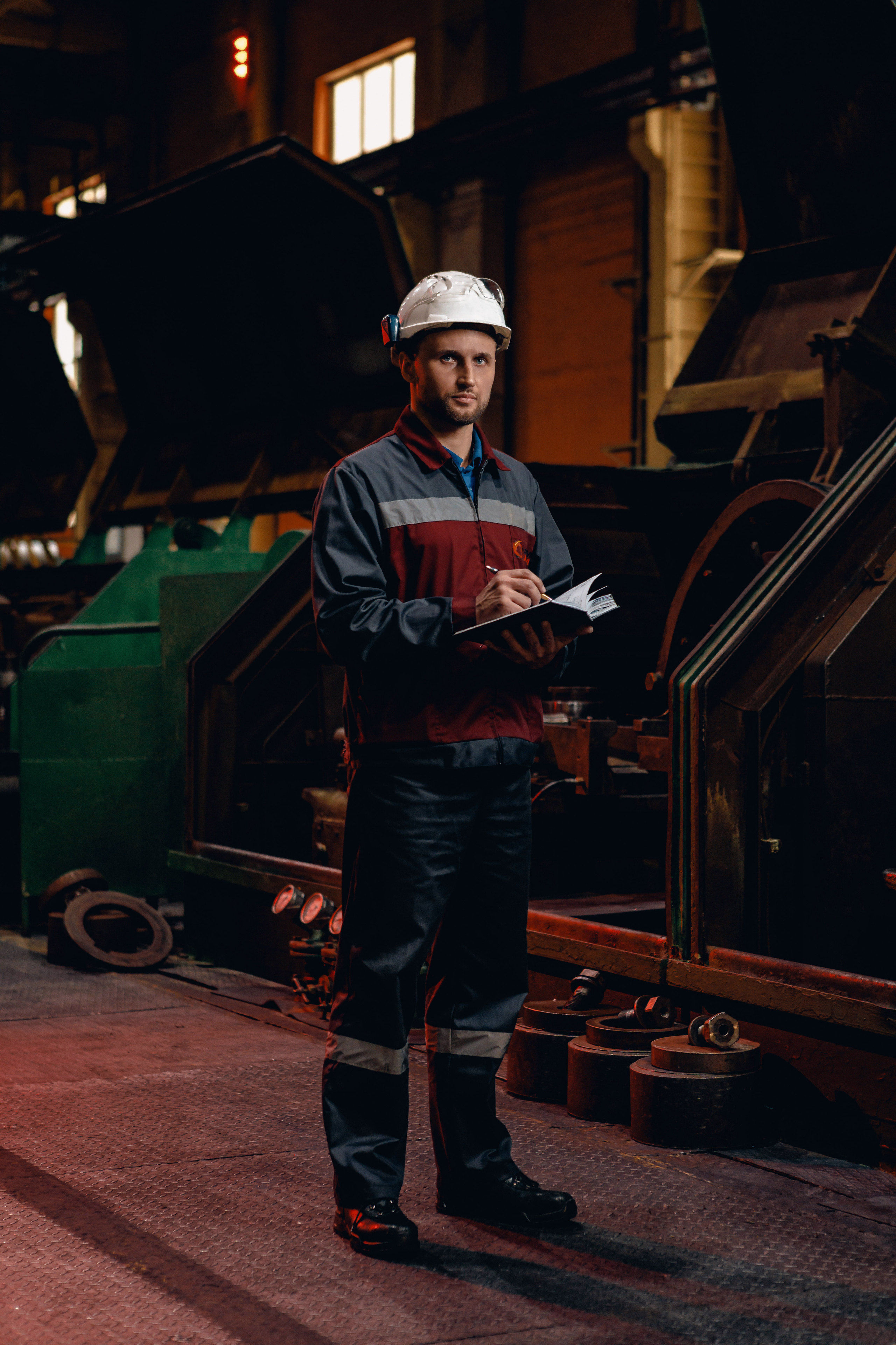 Мастер стоит в цехе с блокнотом в руках