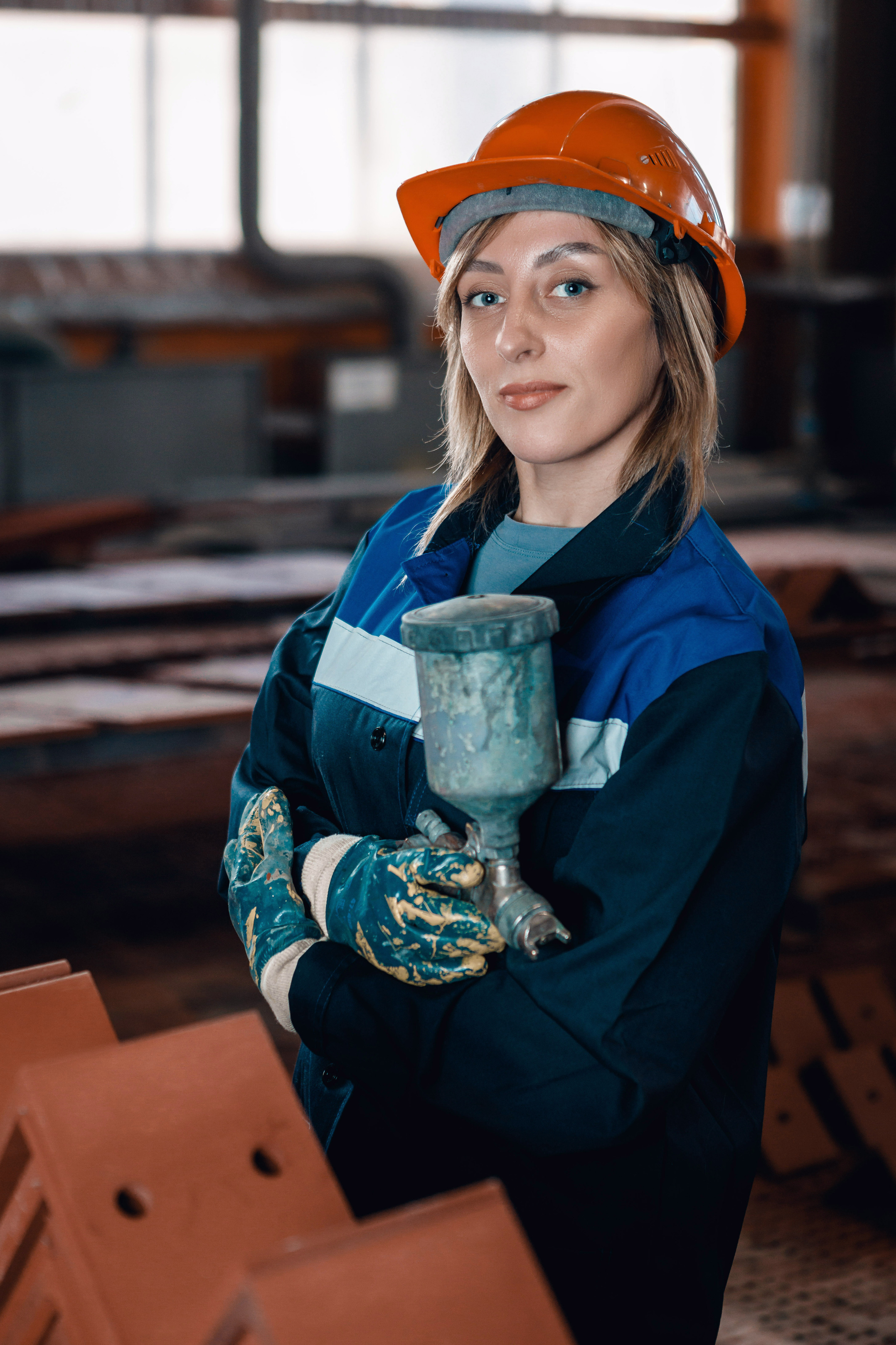 Женщина на производстве позирует в каске