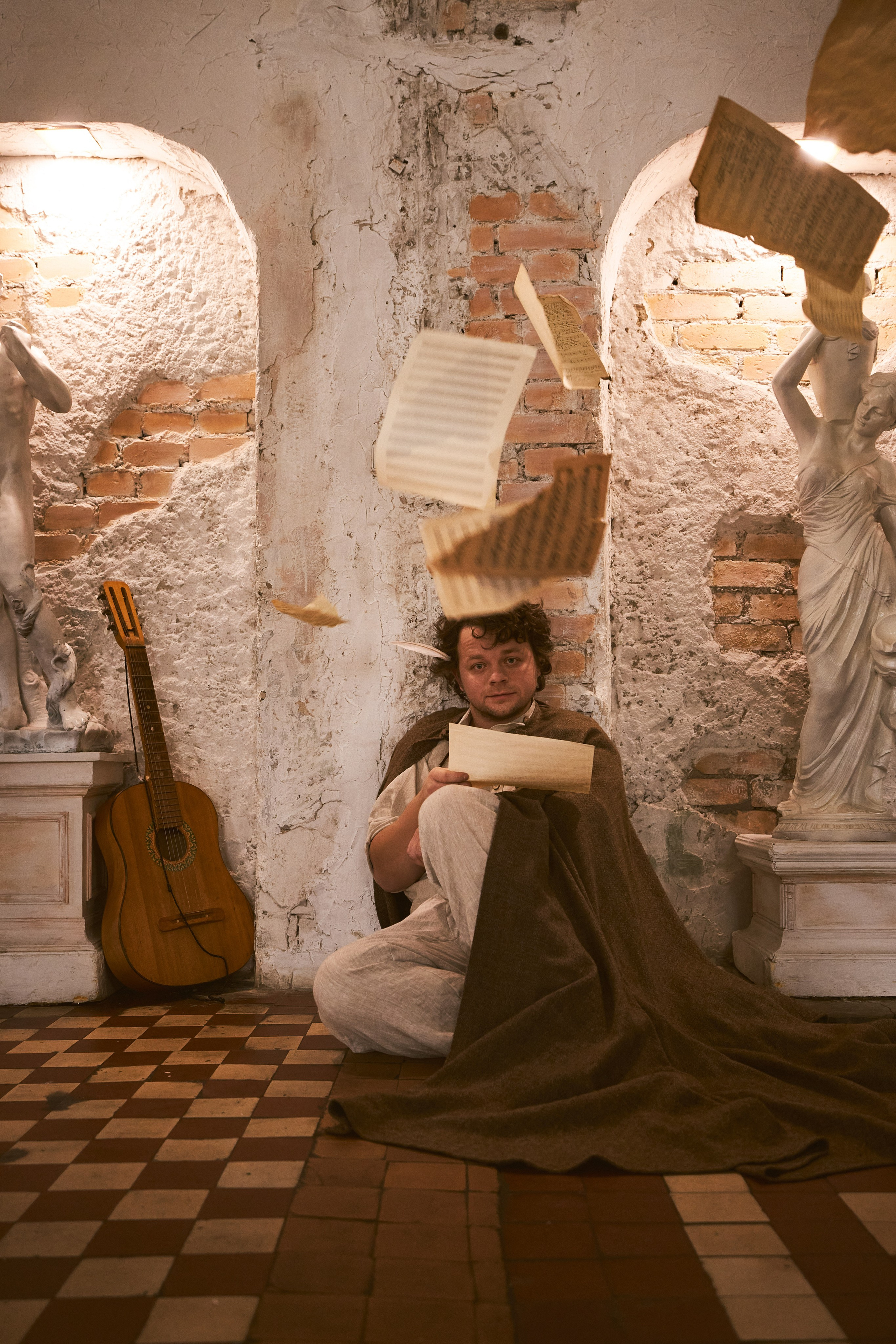 Портрет Сергея Друзьяк, сидящего на полу. Сверху на него падают нотные листы