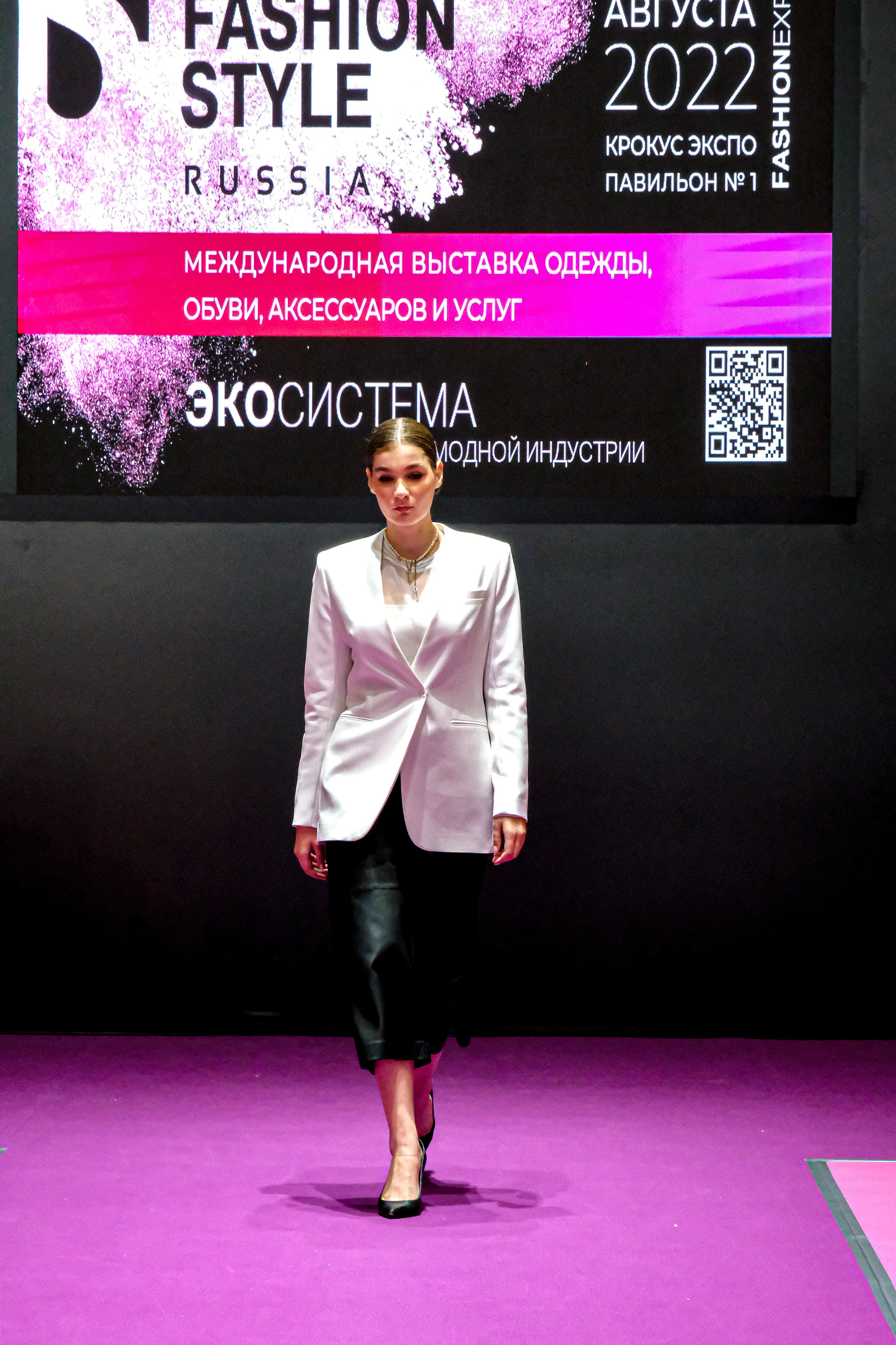  "Модели в ярких нарядах проходят по подиуму во время показа мод, освещенные яркими софитами и окруженные восторженными зрителями."