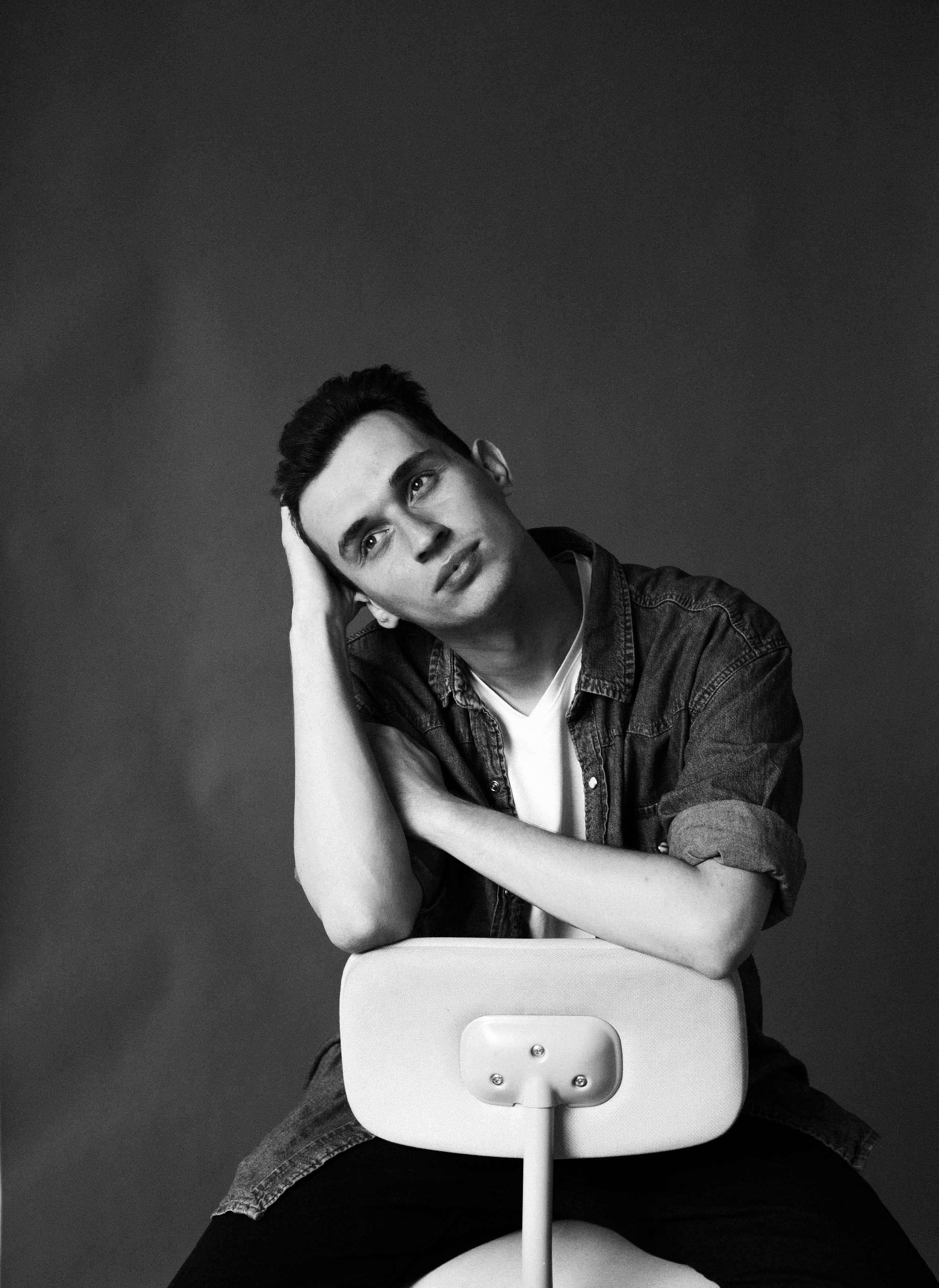 мужской портрет парня в рубашке в студии на стуле 