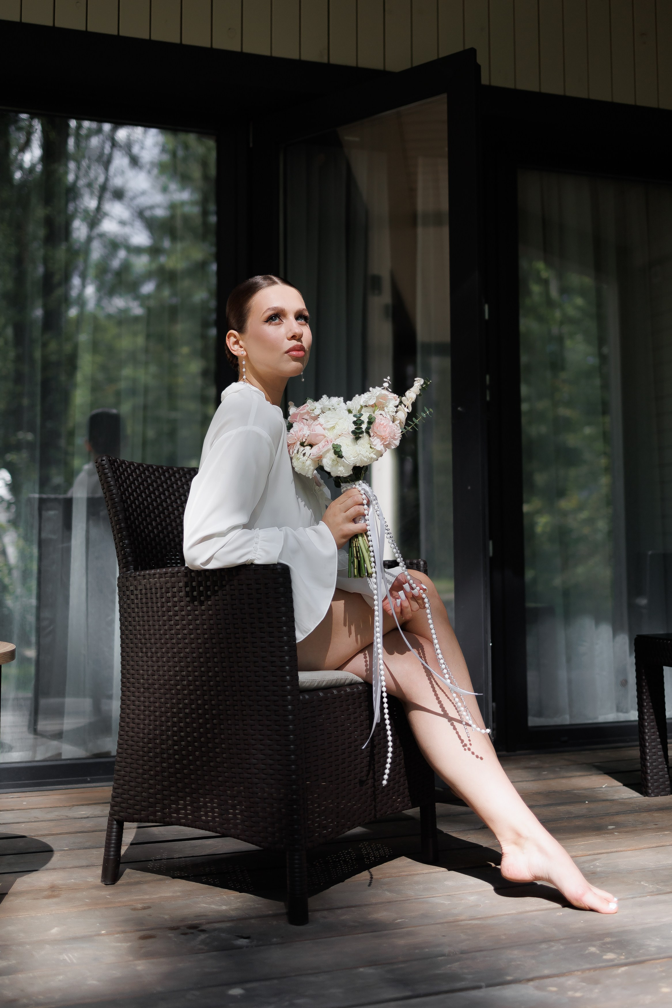 Невеста сидит на стуле на крыльце с букетом