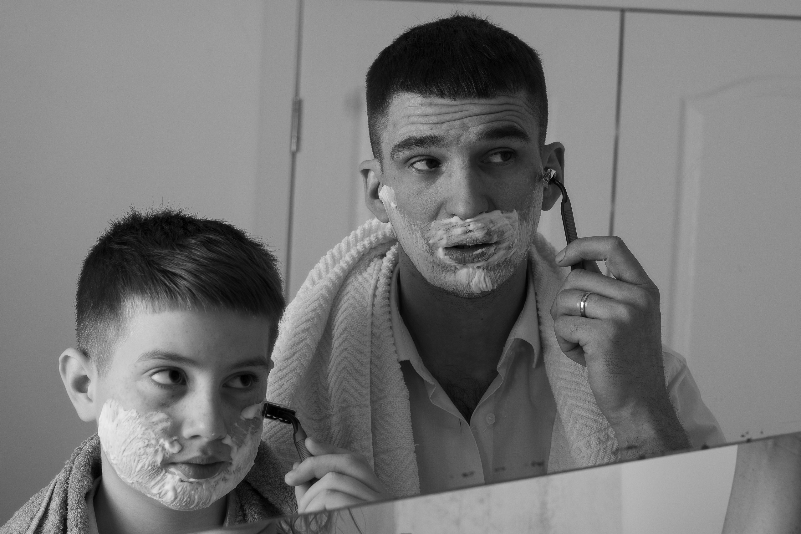 Отец и сын намазаны кремом для бритья и собираются бриться