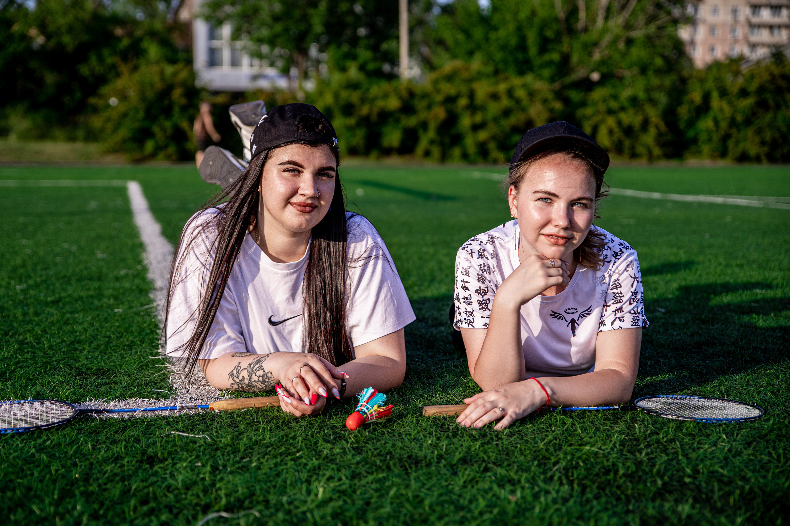 Подружки лежат на зелёной траве, бадминтон