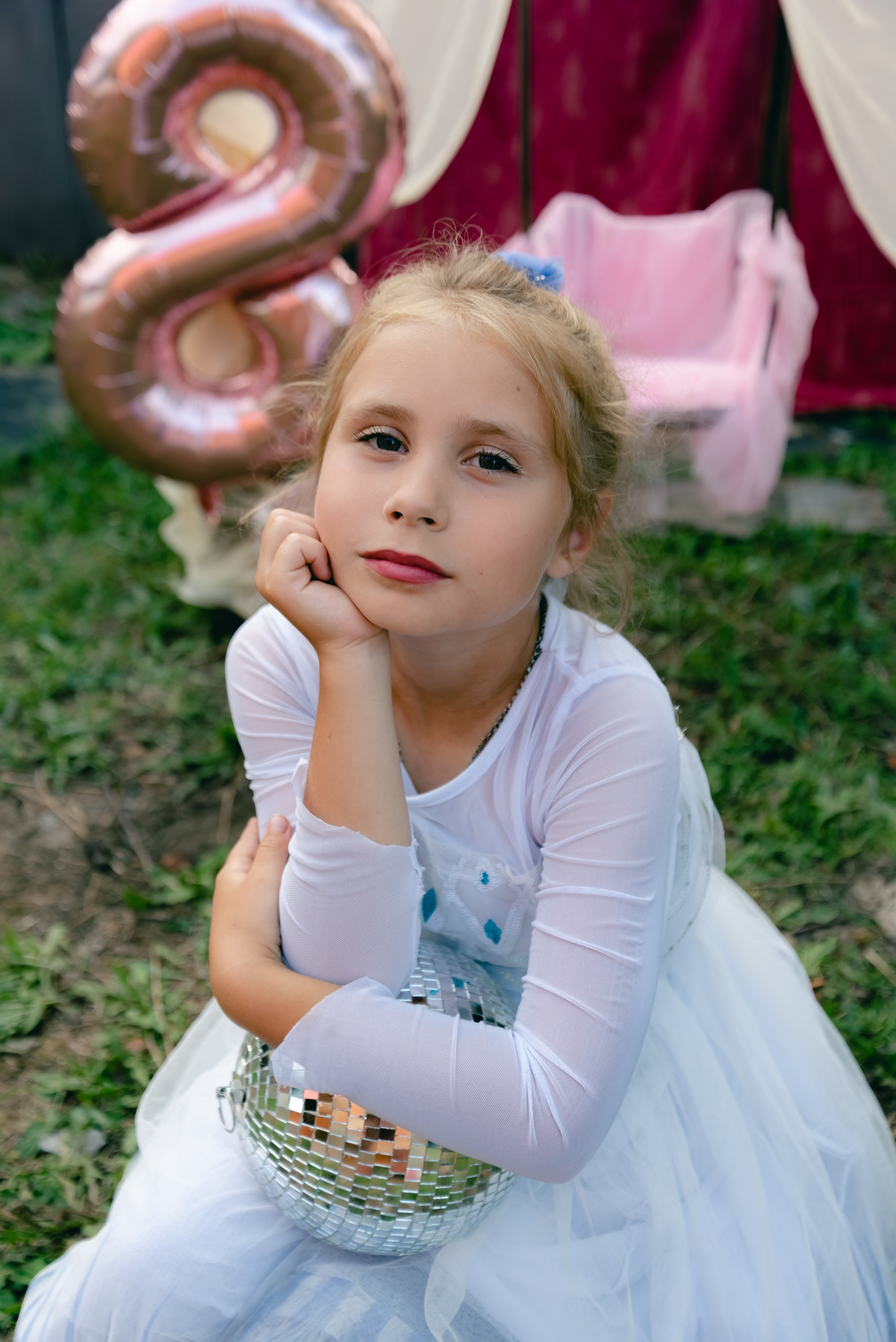 На фото девочка сидит на  шаре, скрестив руки.