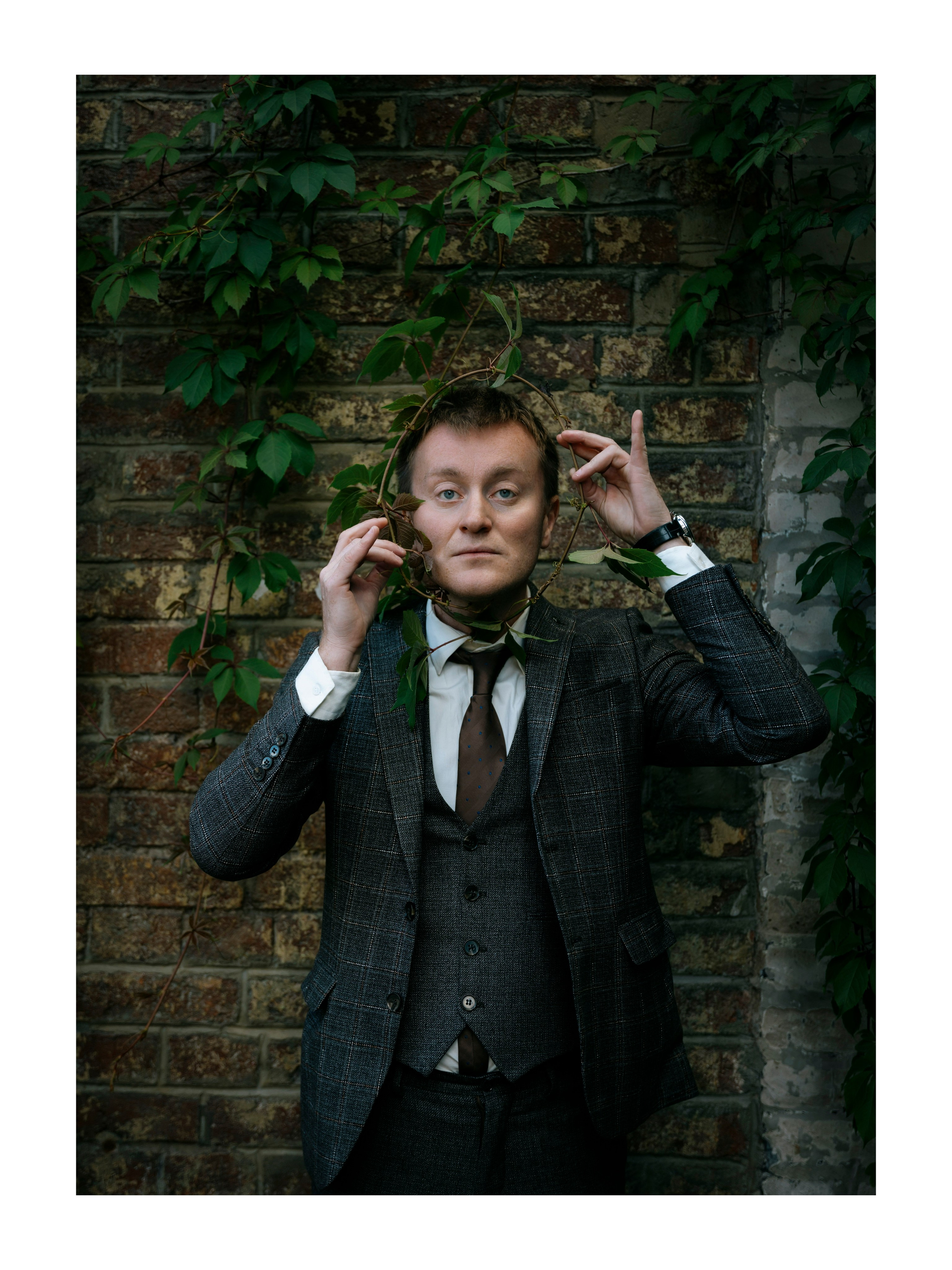 мужчина обвитый ветвями с лепестками