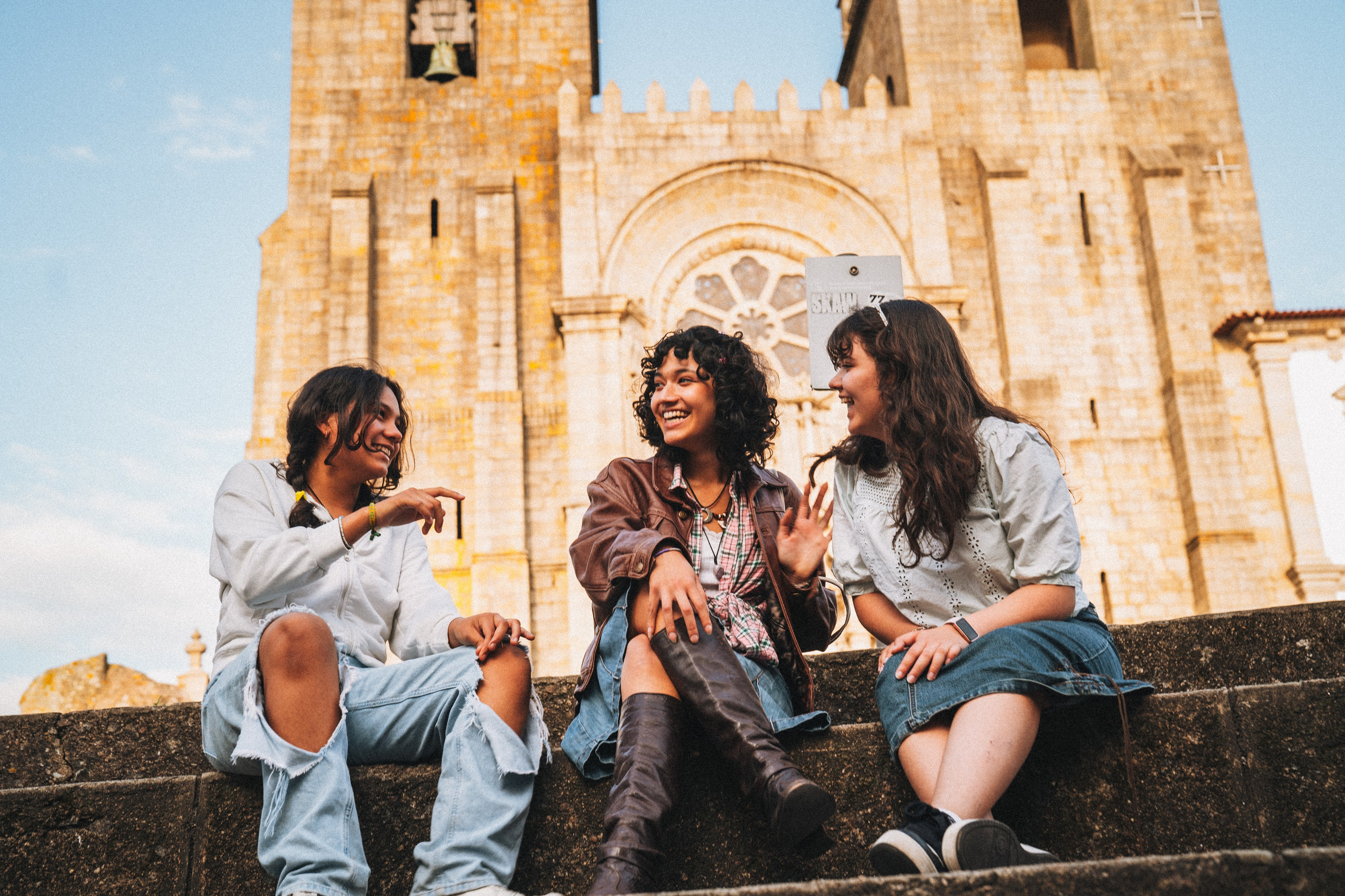 Группа людей семья гуляет по живописной узкой улочке в Португалии, окружённой старыми домами и зеленью.