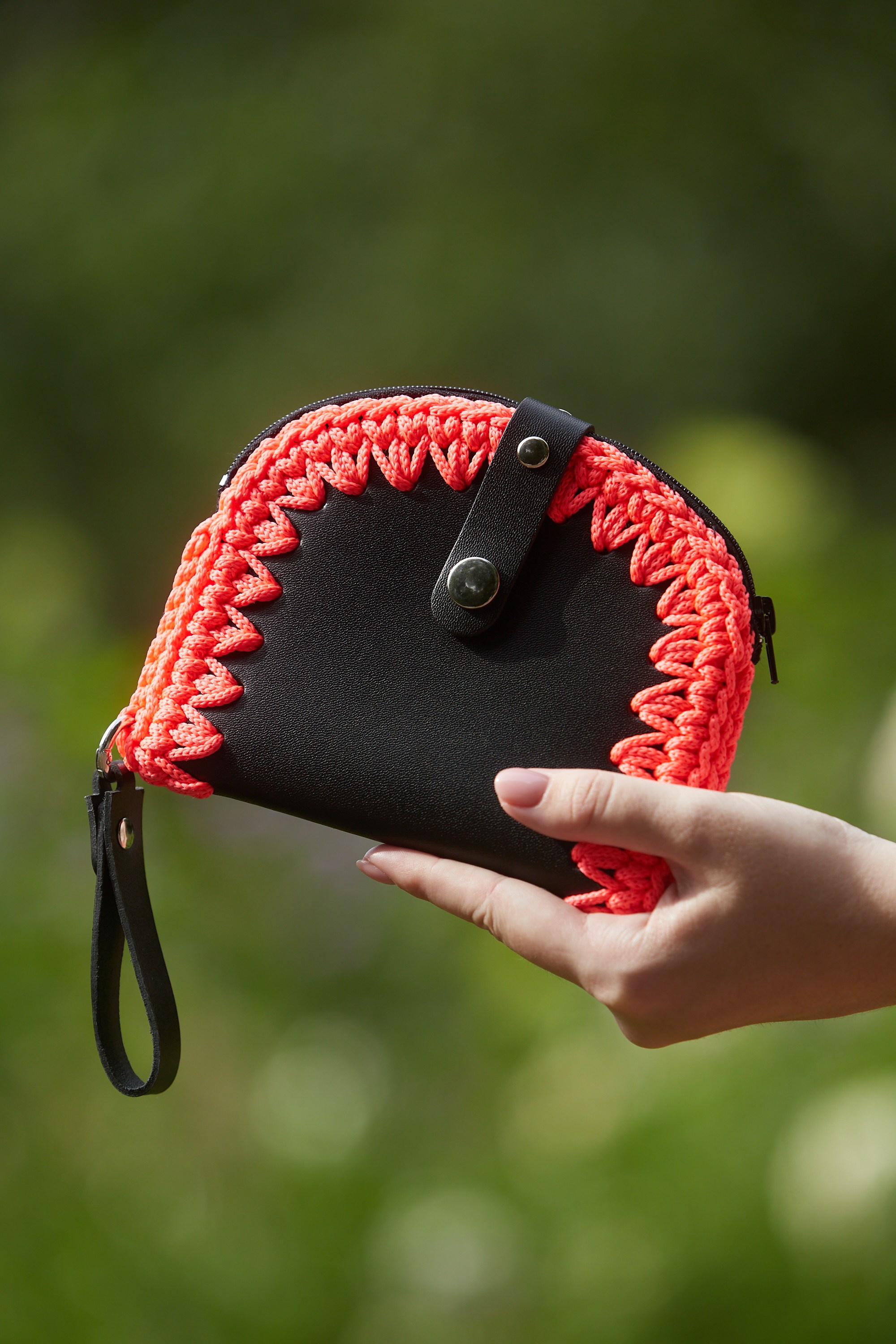 Крупный план чёрного вязаного клатча с красной отделкой.