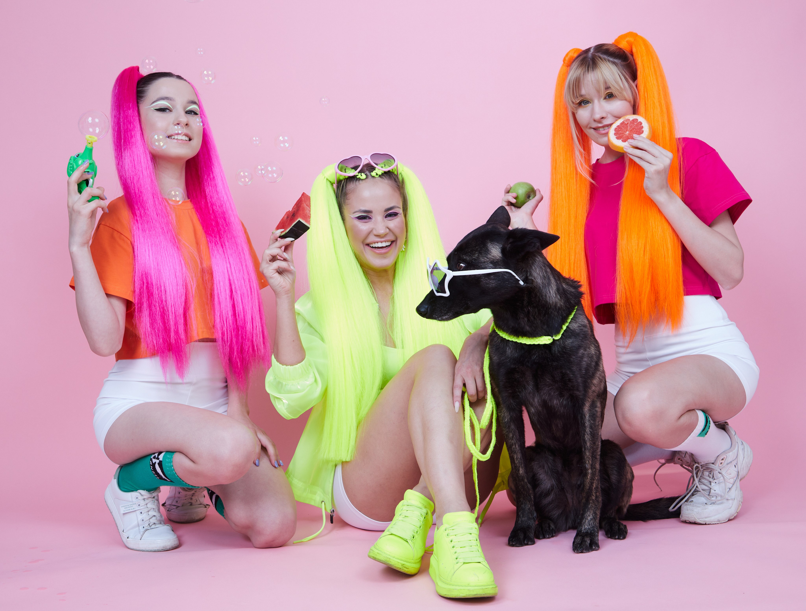 Рекламная съёмка — девушки с неоновыми накладными хвостами и собаками на розовом фоне.