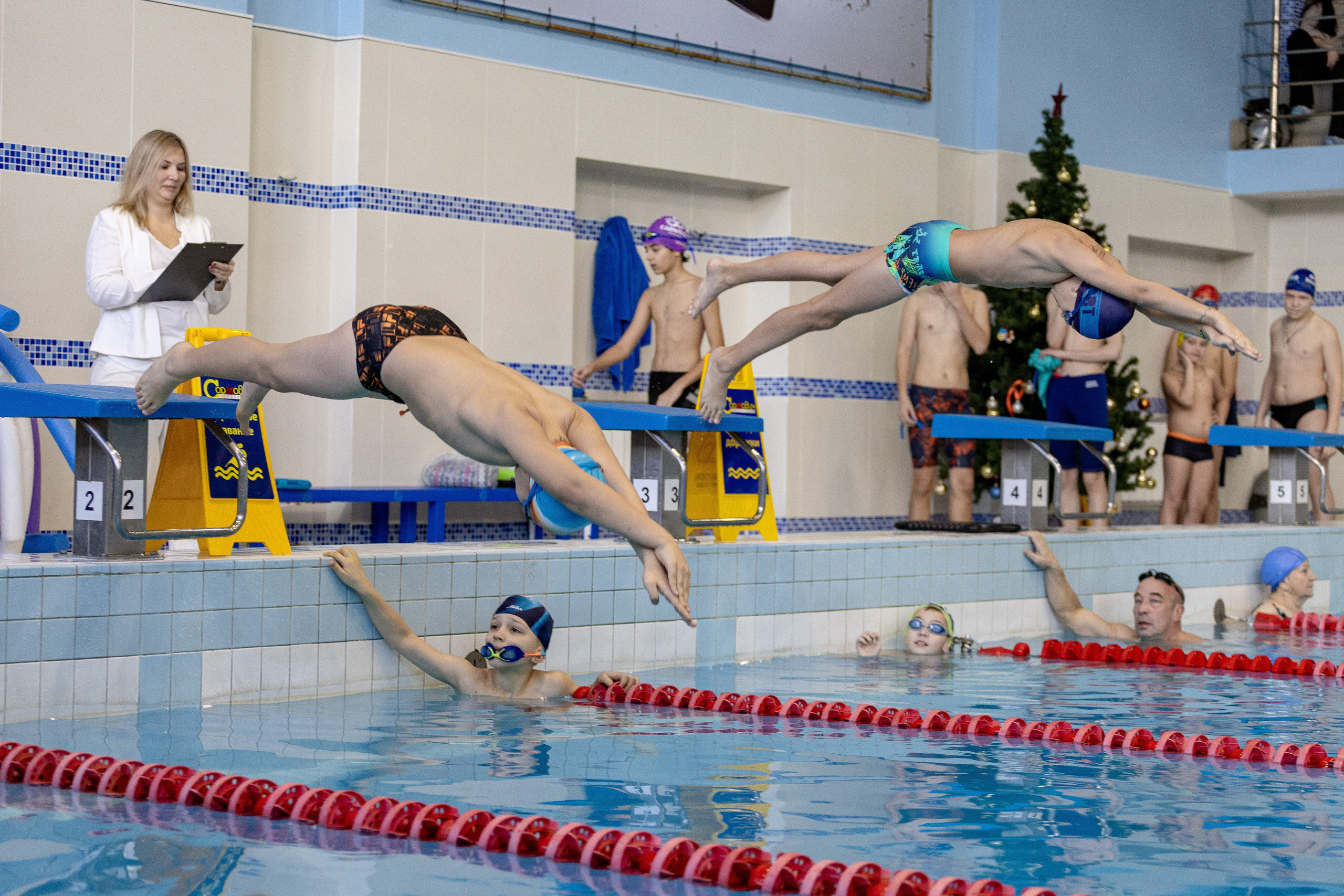 Два пловца совершают прыжок с тумбы в бассейн