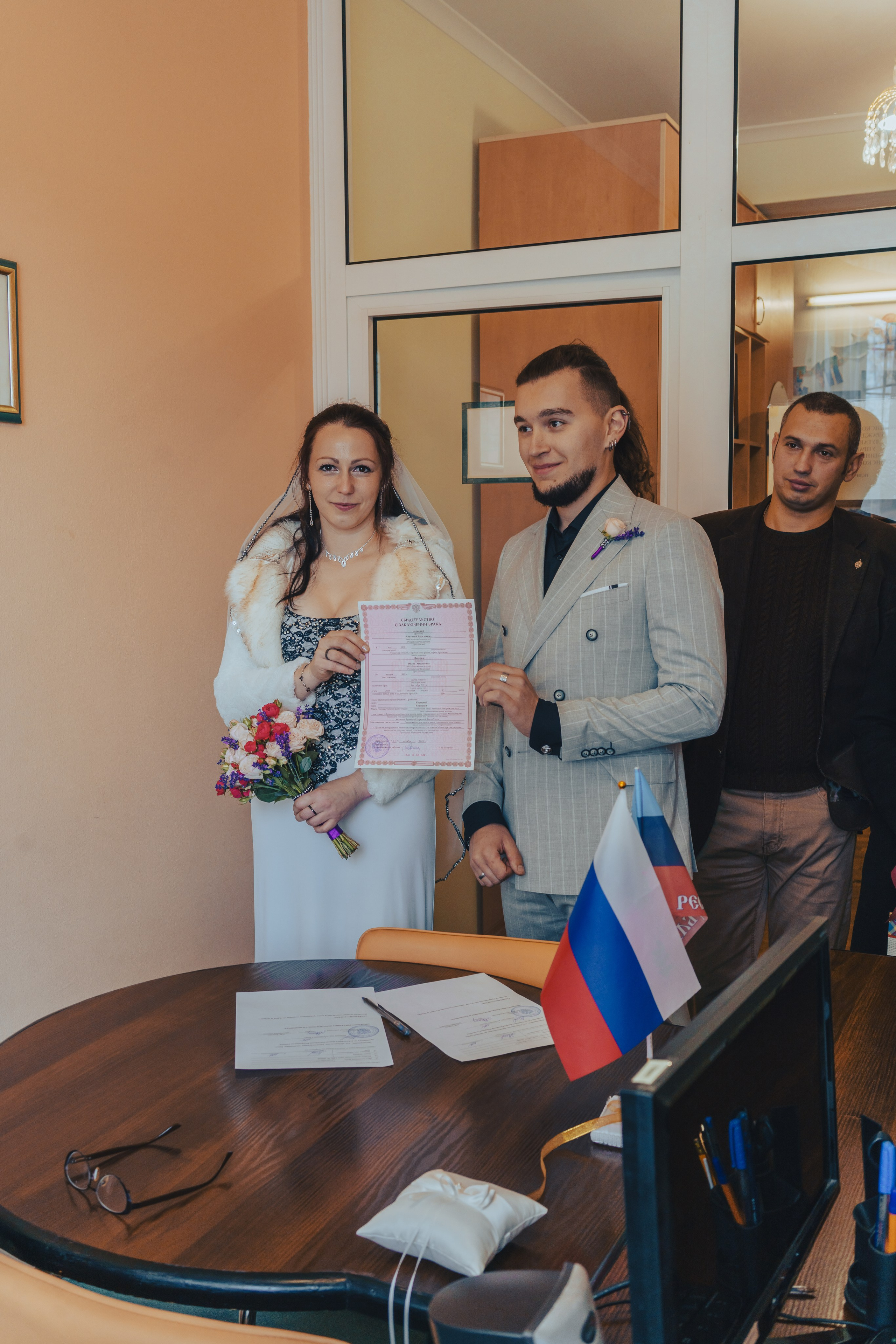 молодые позируют и показывают свидетельство о заключении брака