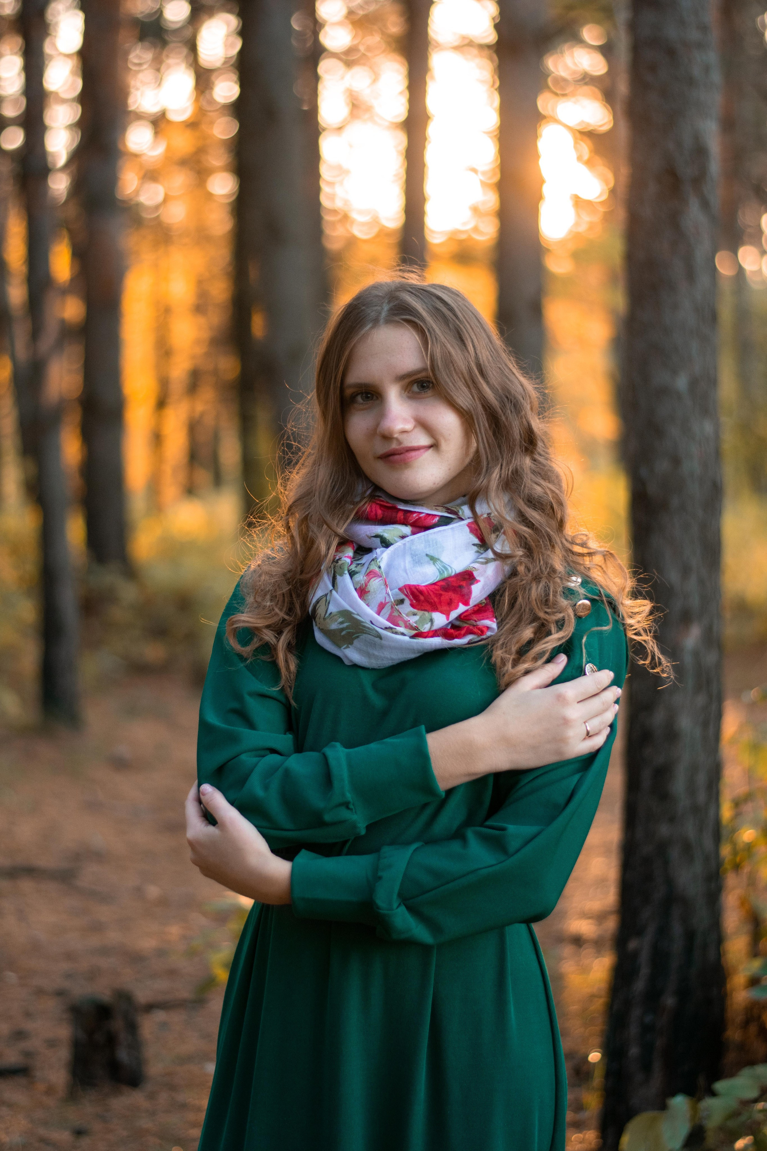 Девушка в сосновом лесу на закате в зеленом платье и кудрявыми волосами
