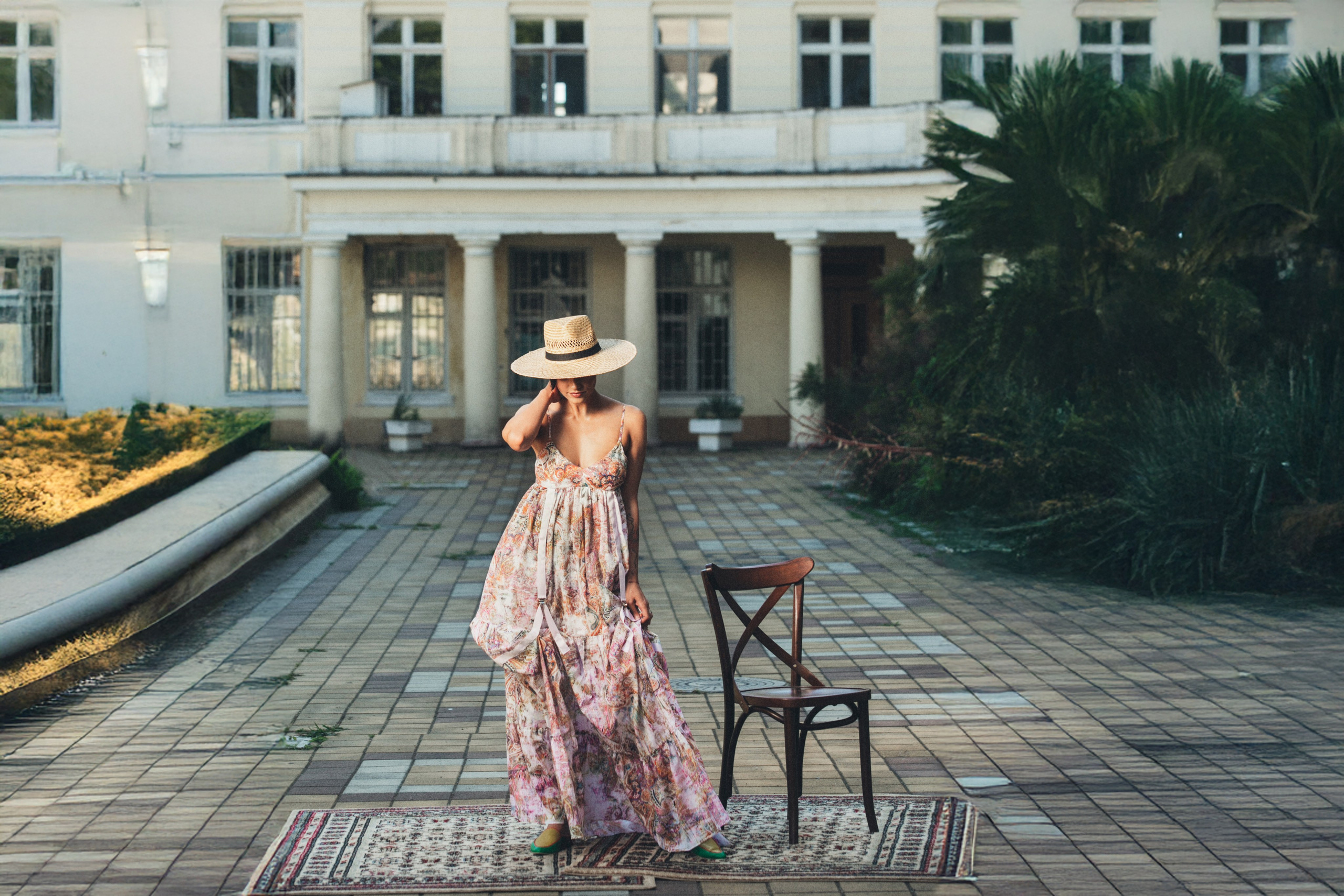 Женственный образ: девушка в длинном цветочном платье и соломенной шляпе позирует во дворе классического особняка — портретный фотограф Галина Скорик.