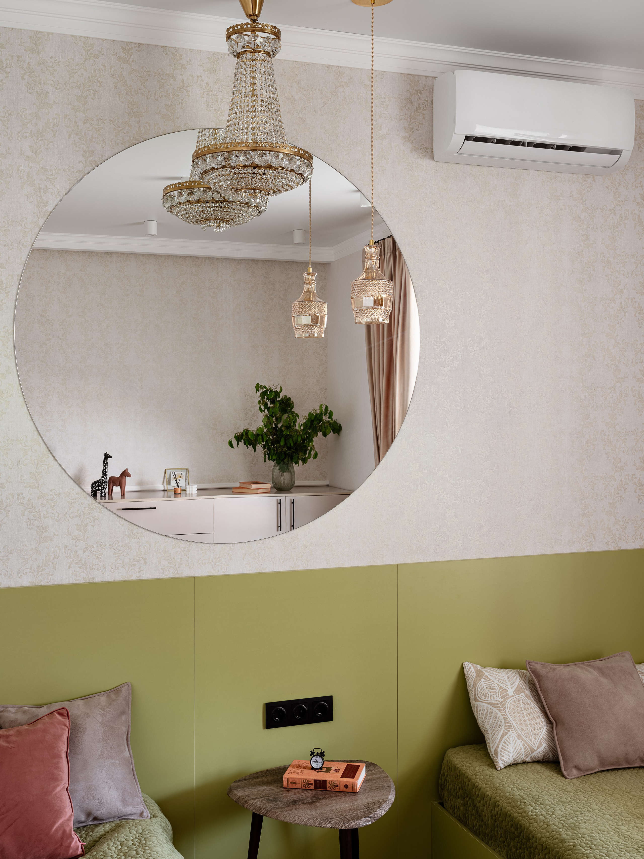 Спальня в современном стиле с большим круглым зеркалом, зелёной стеной у изголовья, хрустальной люстрой и подвесными светильниками, уютное оформление с растениями, дизайнер Алина Чередниченко, фотограф Сергей Денисенко