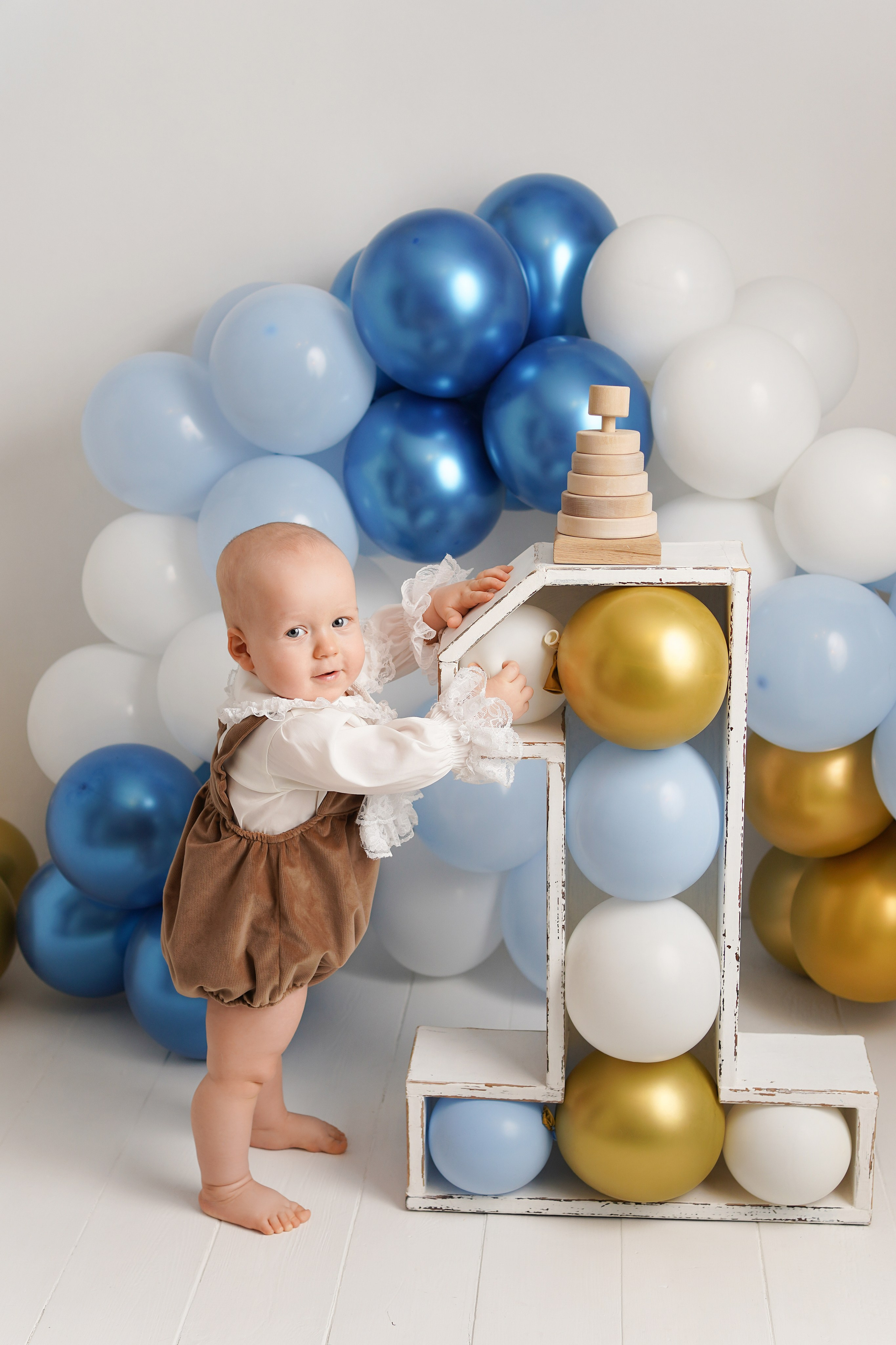 Мальчик отмечает Первый годик  стоит рядом с огромной единицей.