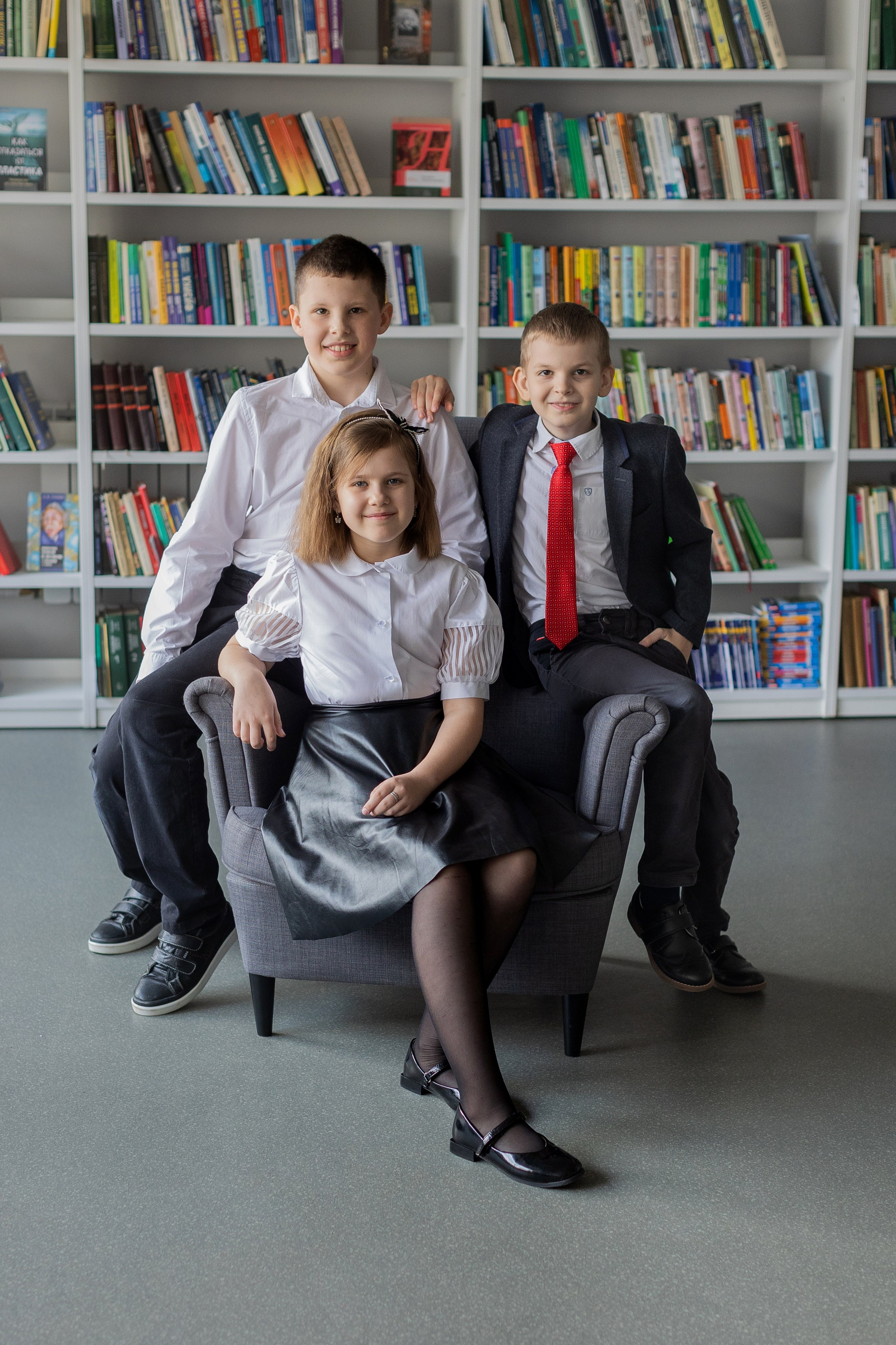 Мальчики и девочка сидят на стуле