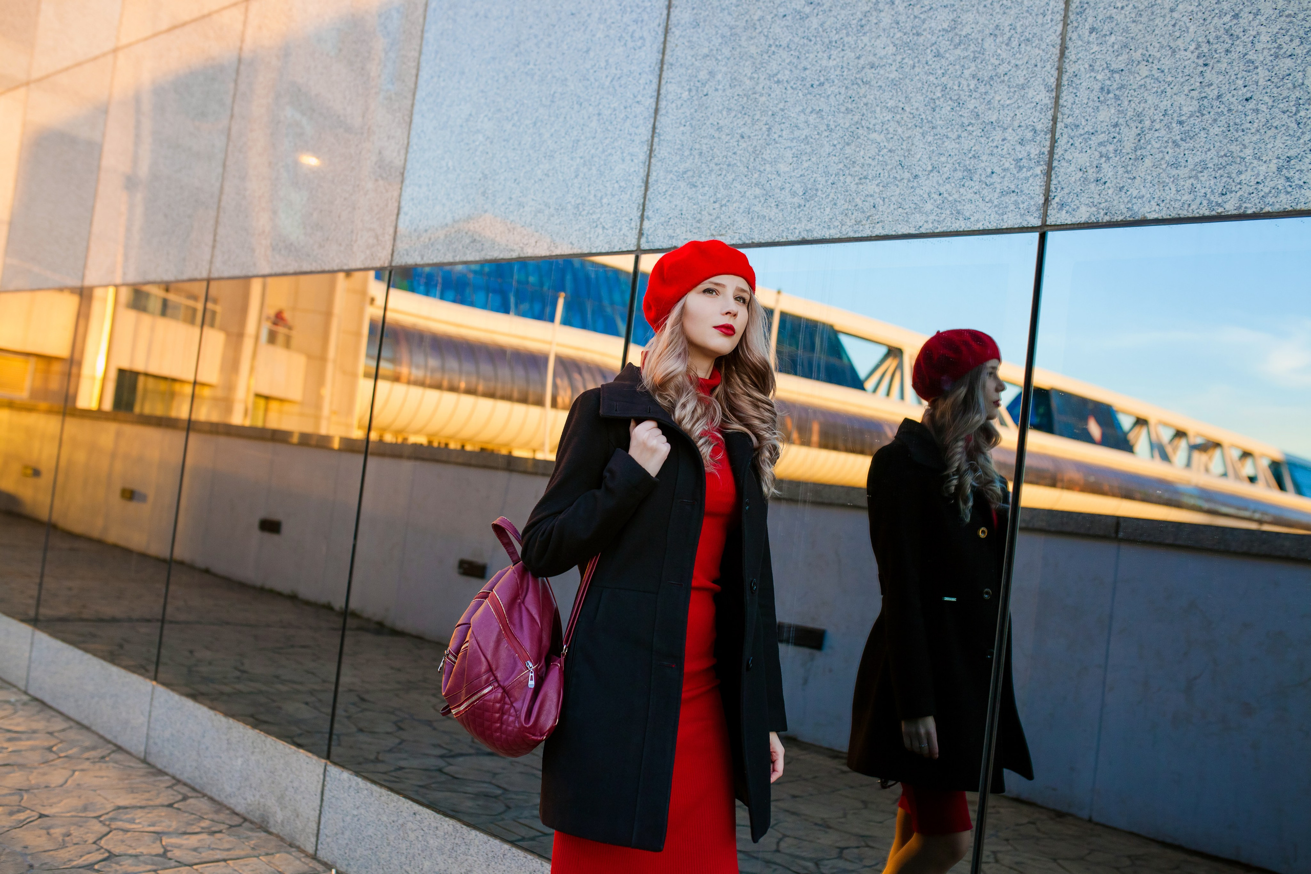 Девушка идёт вдоль большого зеркала и отражается в нём