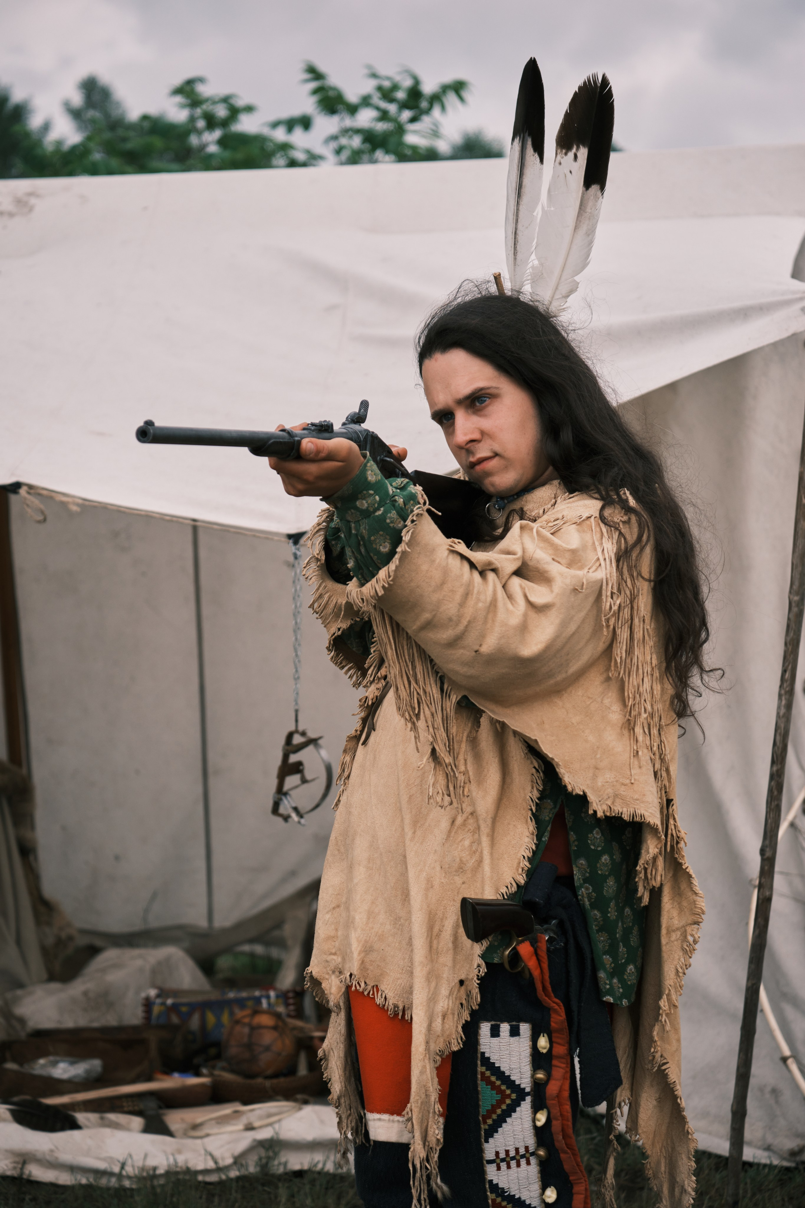 Индеец с перьями на голове целиться из ружья 