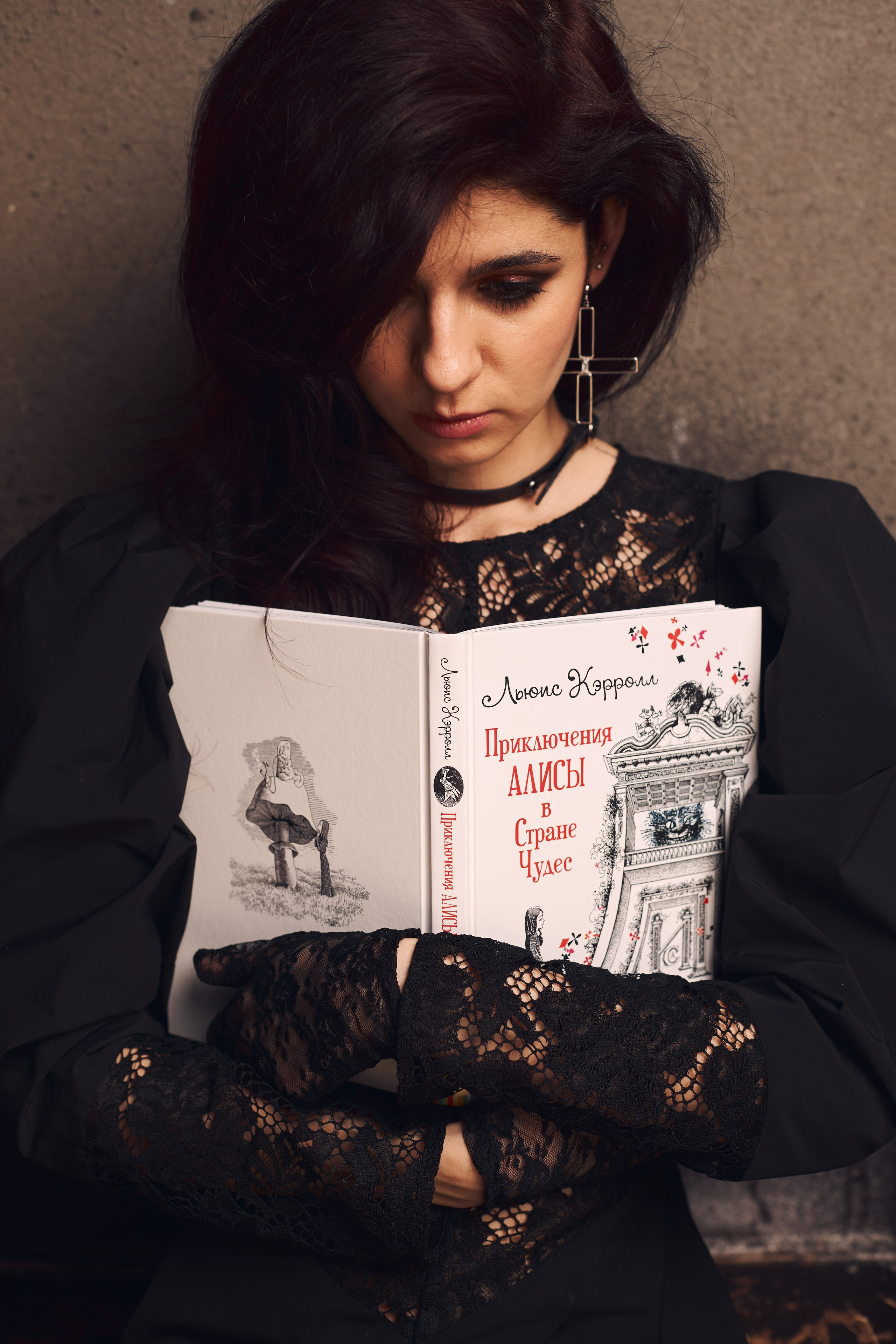 Девушка прислонила к себе книгу "Алиса в Стране Чудес"