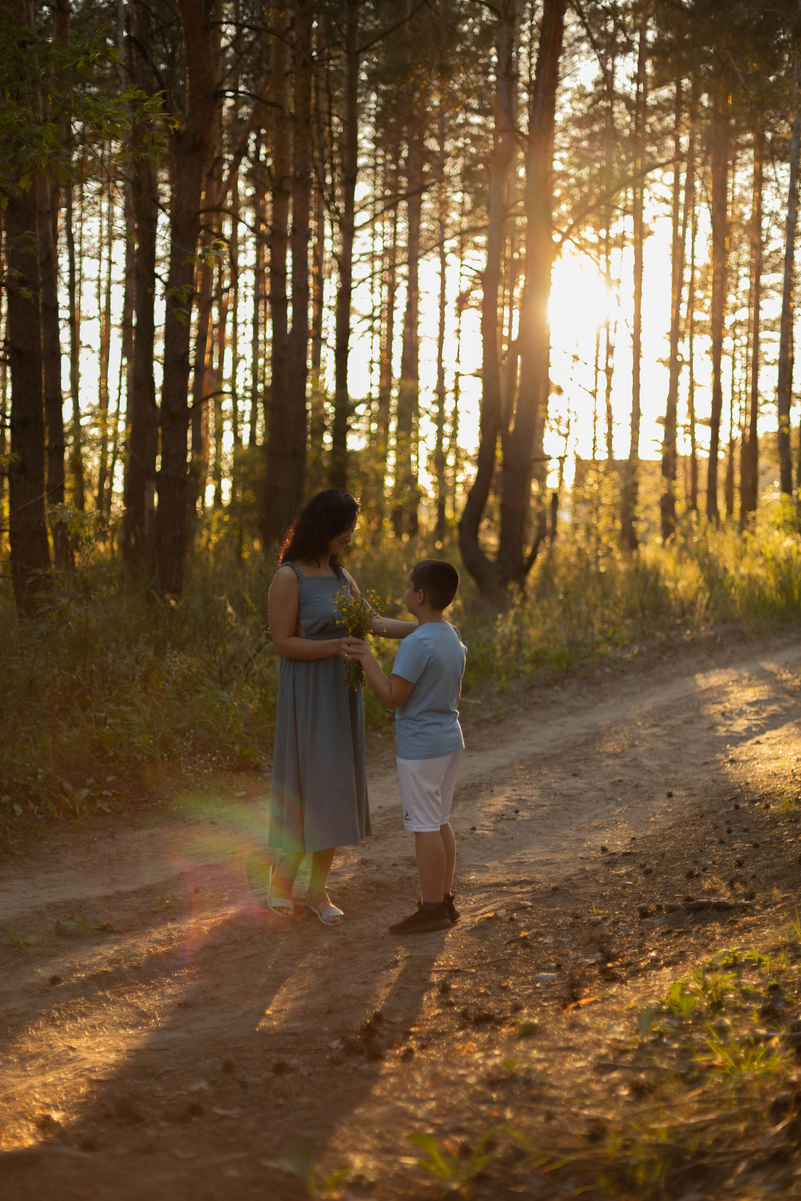 Мама с сыном в сосновом лесу, семейная фотосессия летом, мальчик подарил маме букет