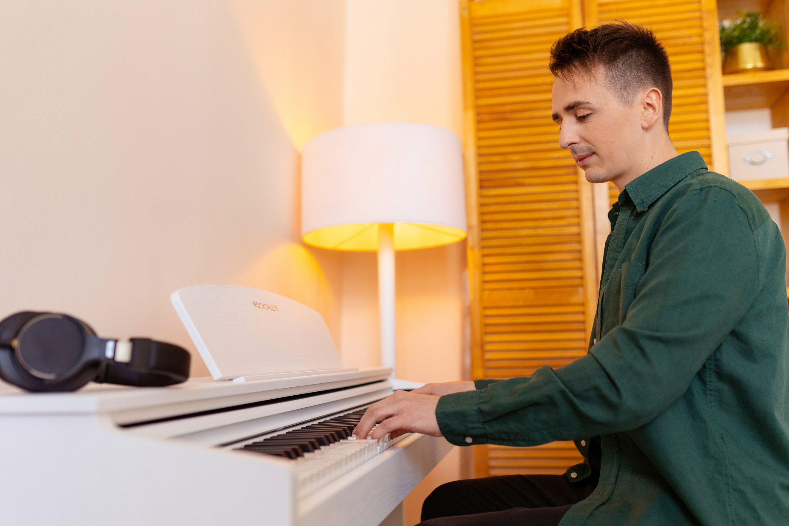 Молодой человек играет на белом фортепиано