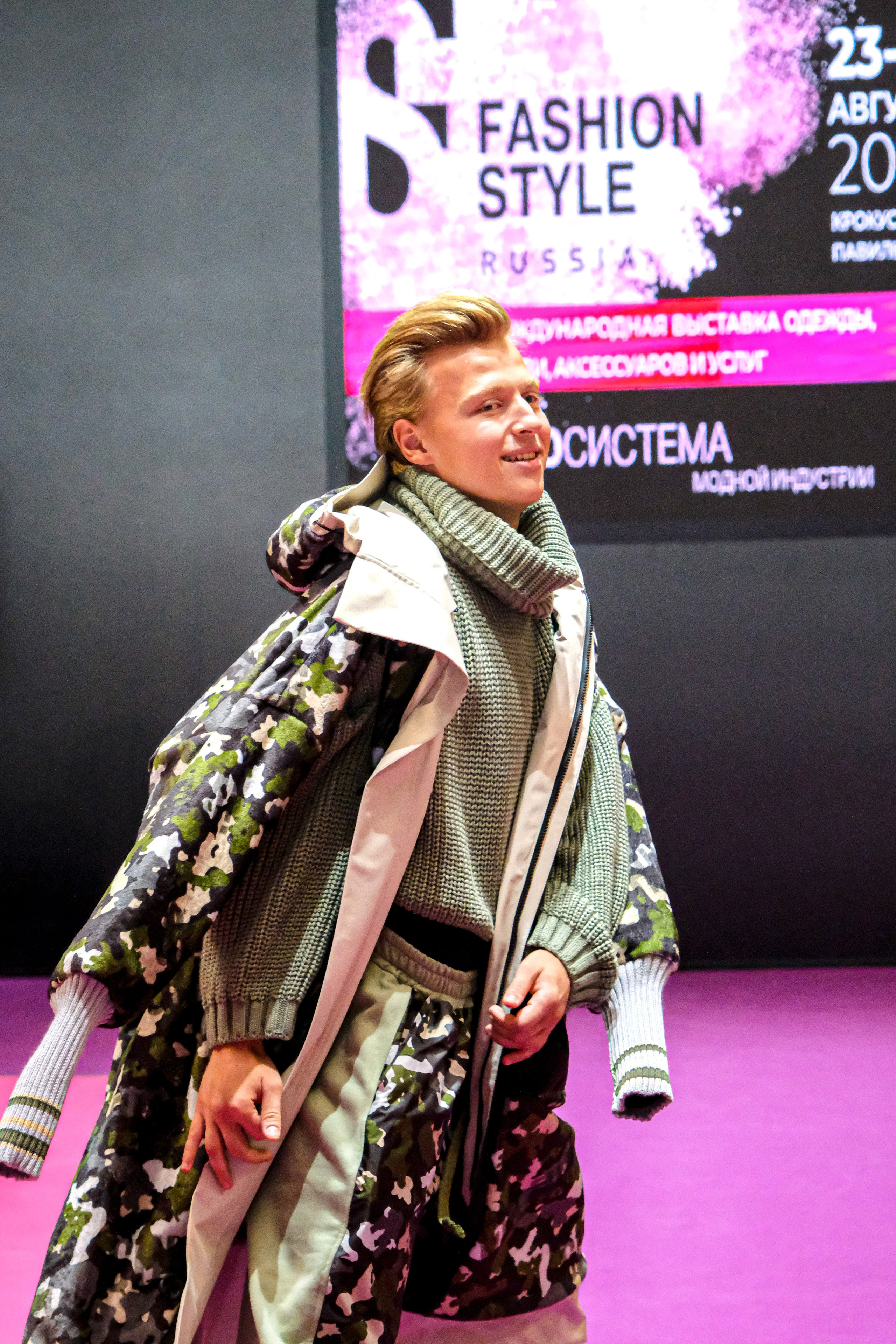  "Модели в ярких нарядах проходят по подиуму во время показа мод, освещенные яркими софитами и окруженные восторженными зрителями."