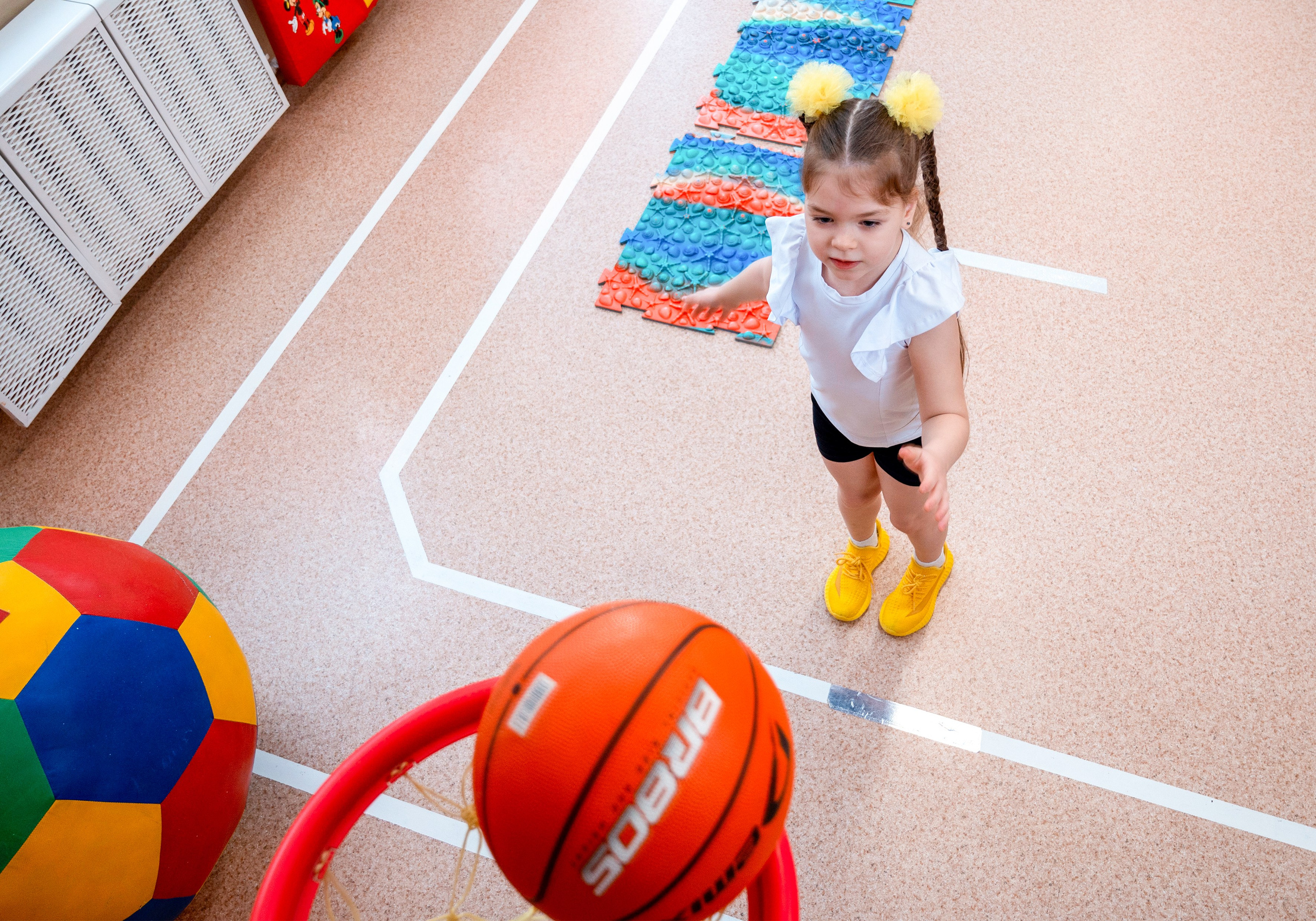 Девочка с мячом в спортзале детского сада