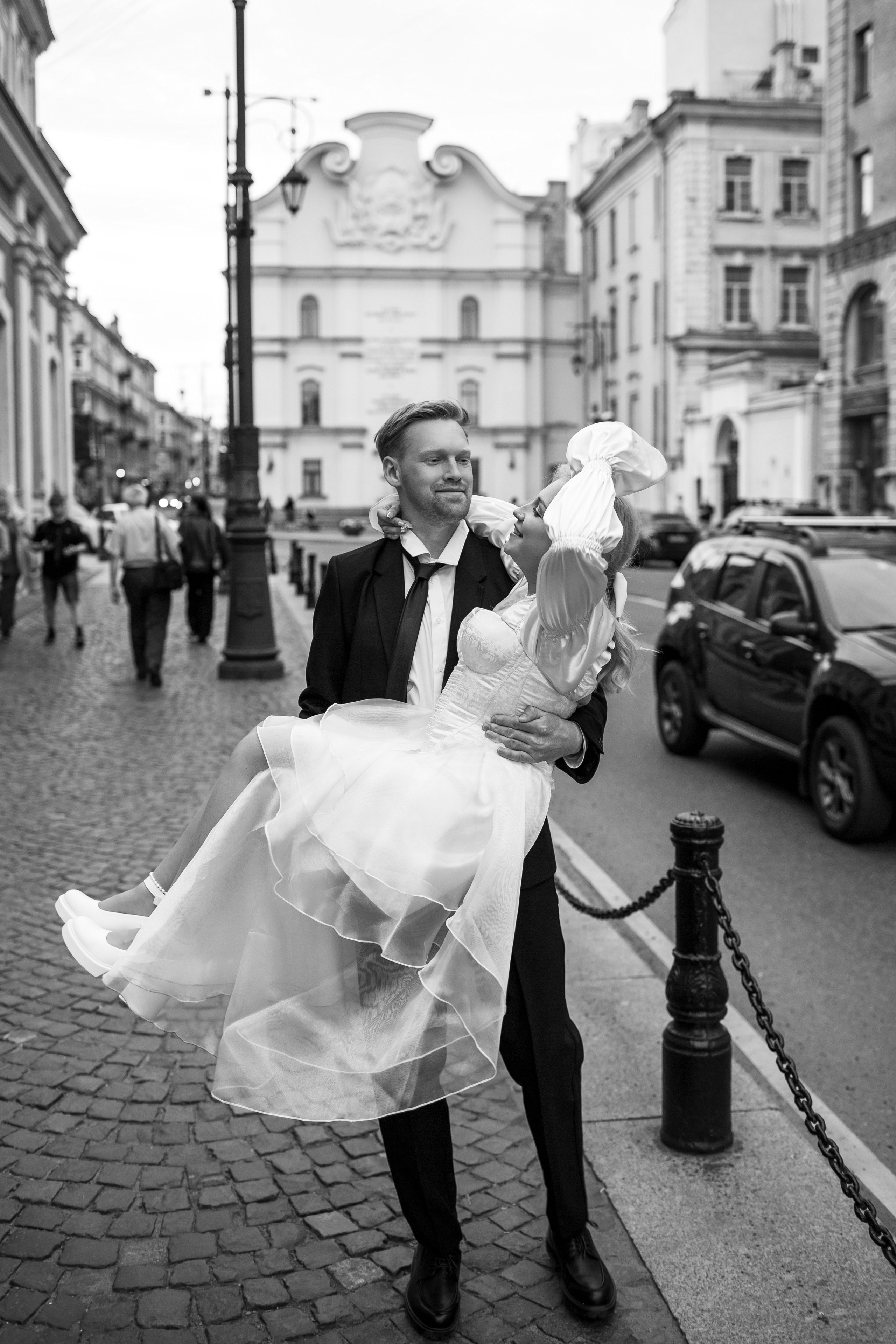 Эстетичная свадебная черно-белая фотография: жених несет невесту на руках.