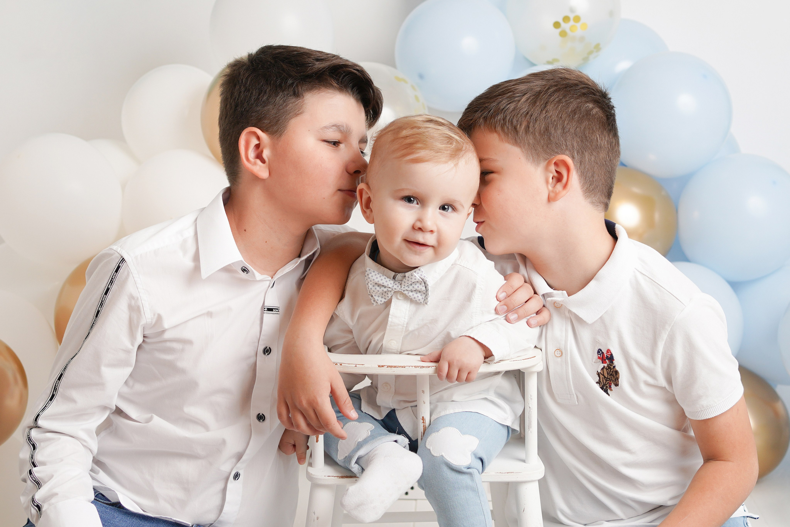 На фото портрет трех братьев. Старшие мальчики целуют самого младшего брата.