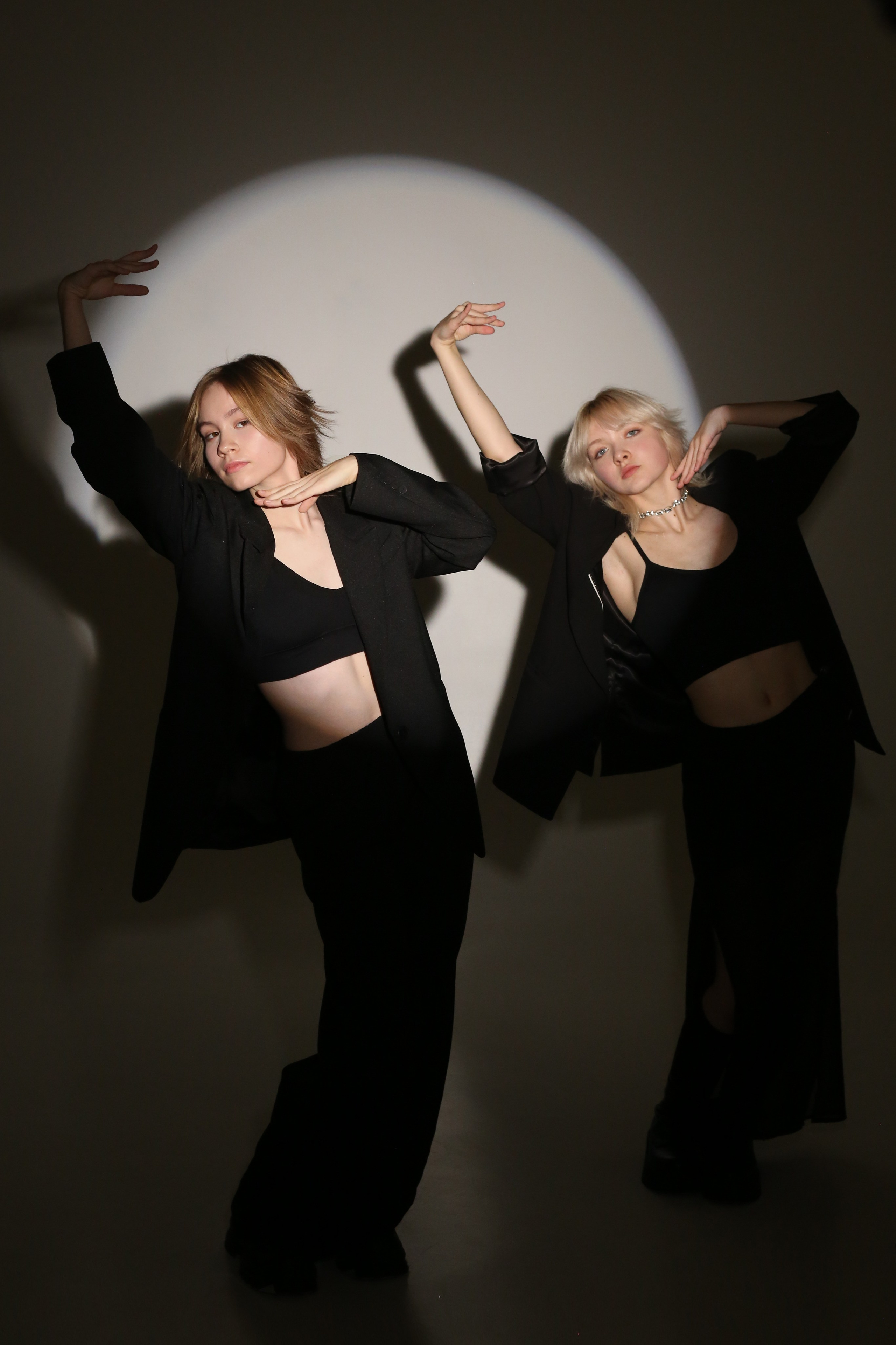 Фотосессия «Геометрия»: две девушки в черных костюмах позируют в круге света