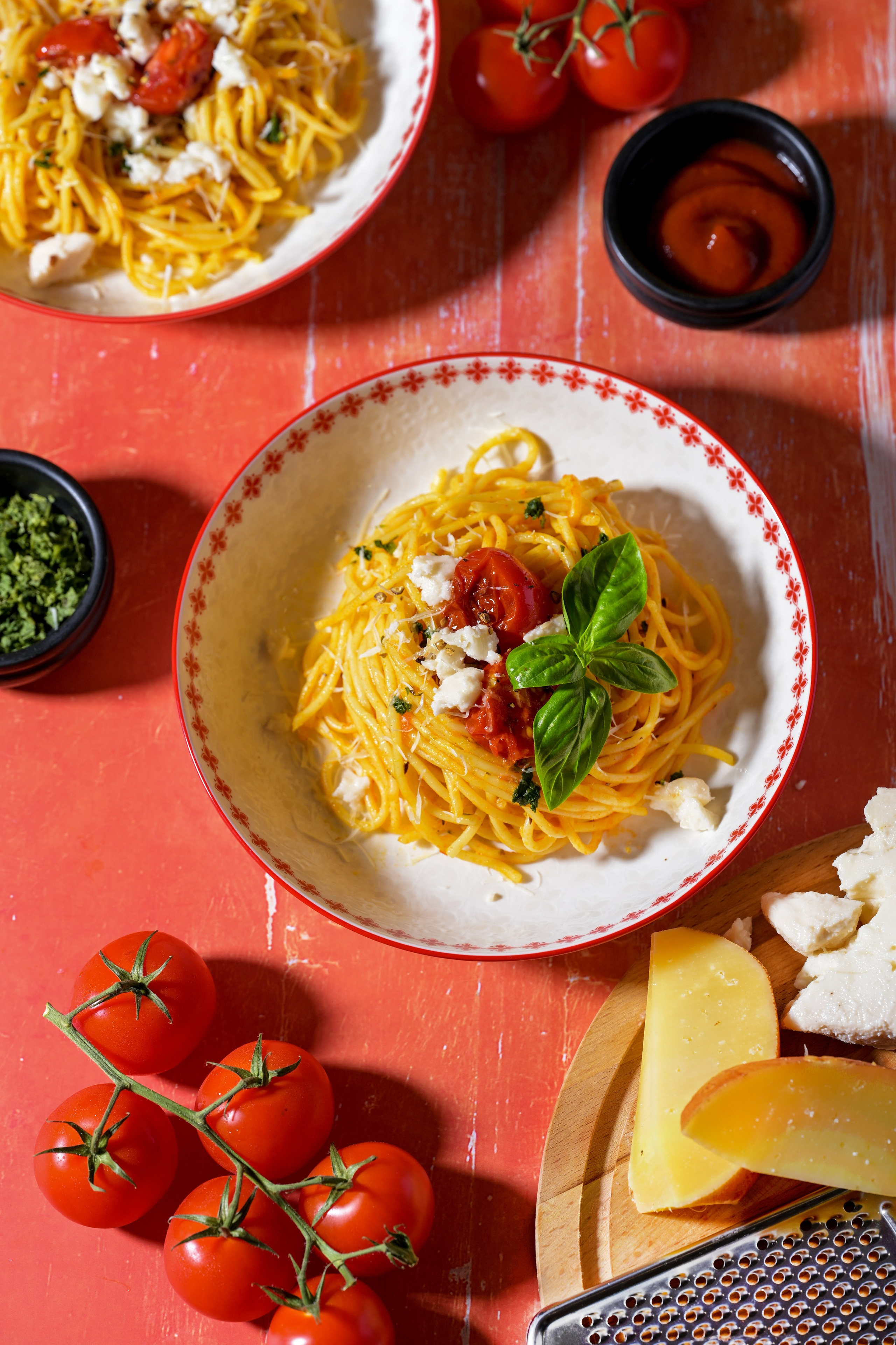 Тарелка с пастой с томатами, сыром, базиликом,  на красном фоне 