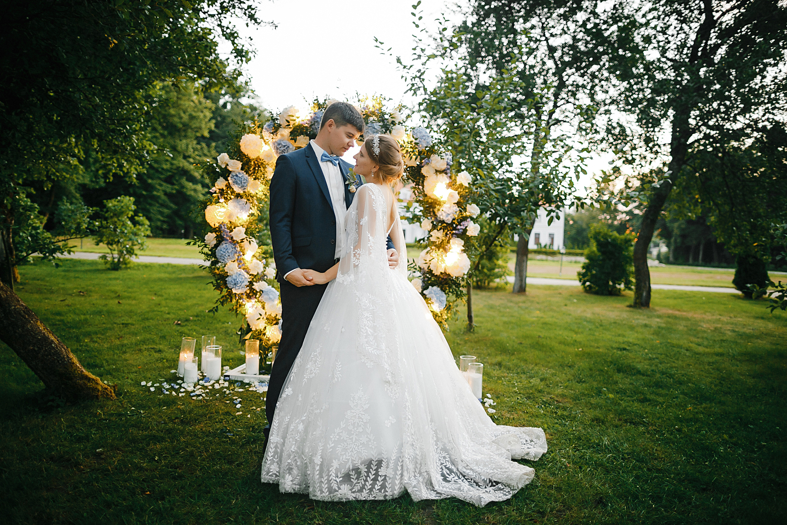 Жених и невеста обнимаются у арки выездной регистрации в Усадьбе Калининград