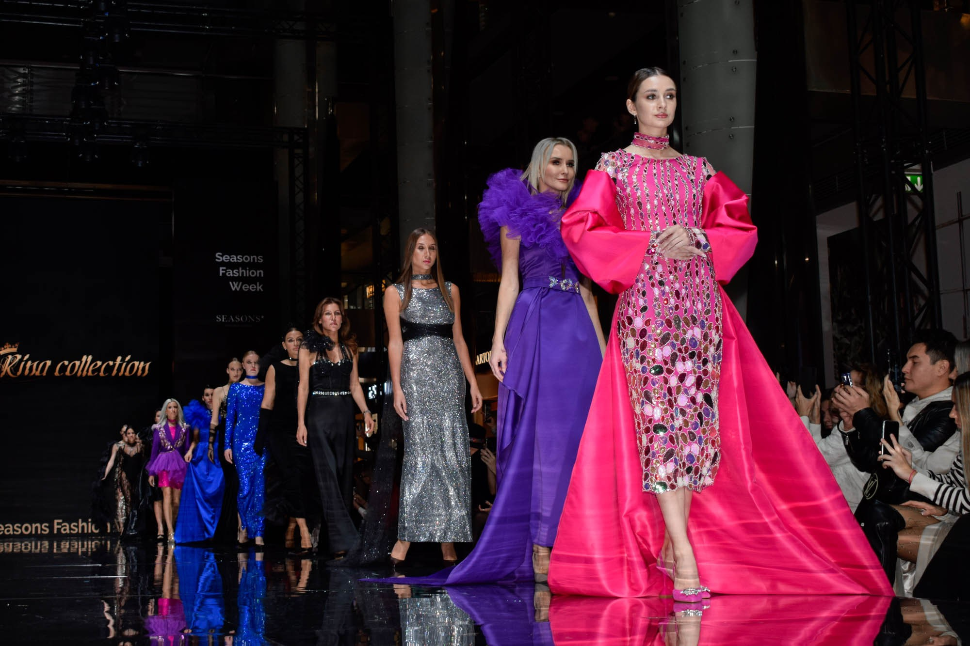Дефиле моделей в красивых цветных костюмах на сцене