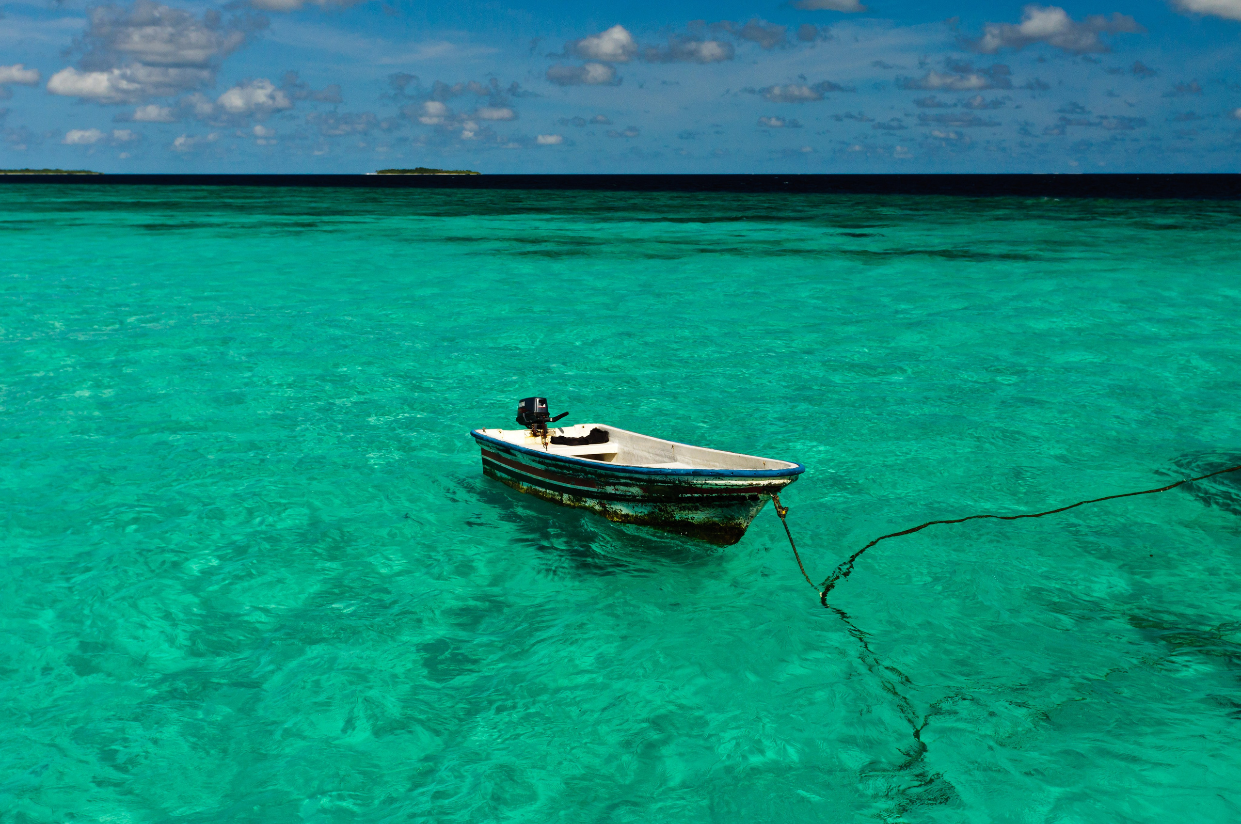 Рыбацкая лодка в прозрачной бирюзовой вводе. Мальдивы