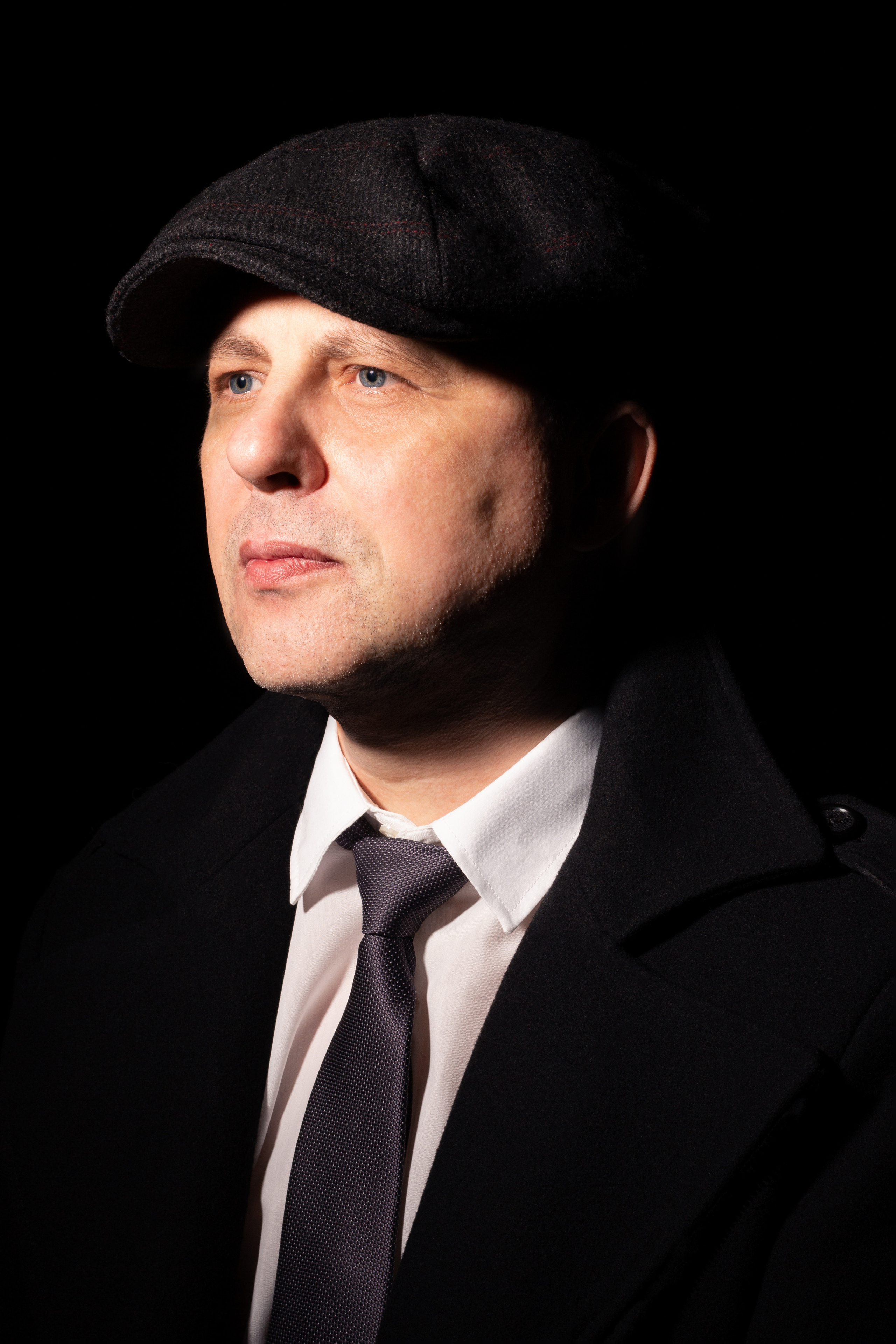 Мужчина в черном пальто и в кепке.