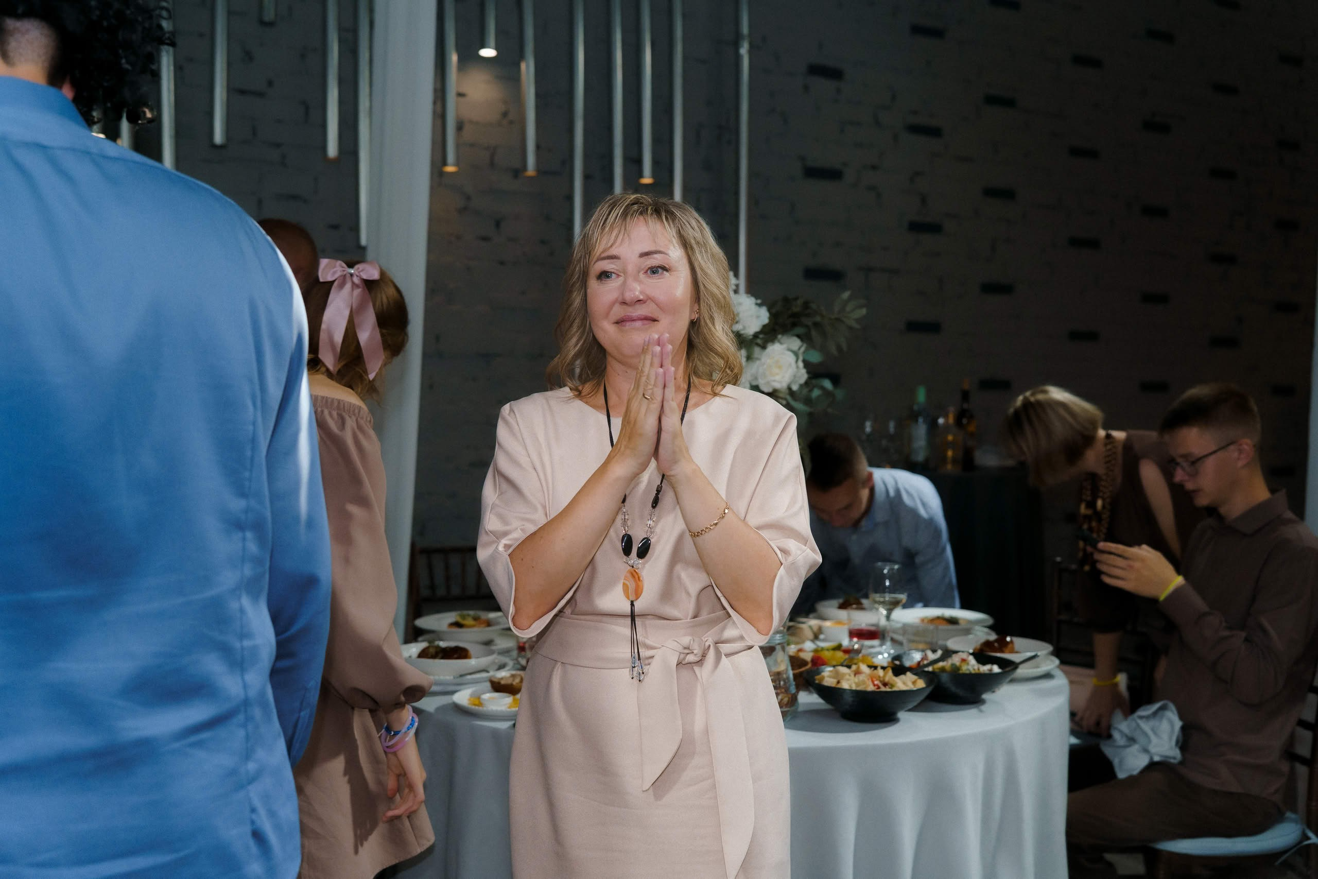 Гостья с букетом аплодирует и улыбается во время банкета