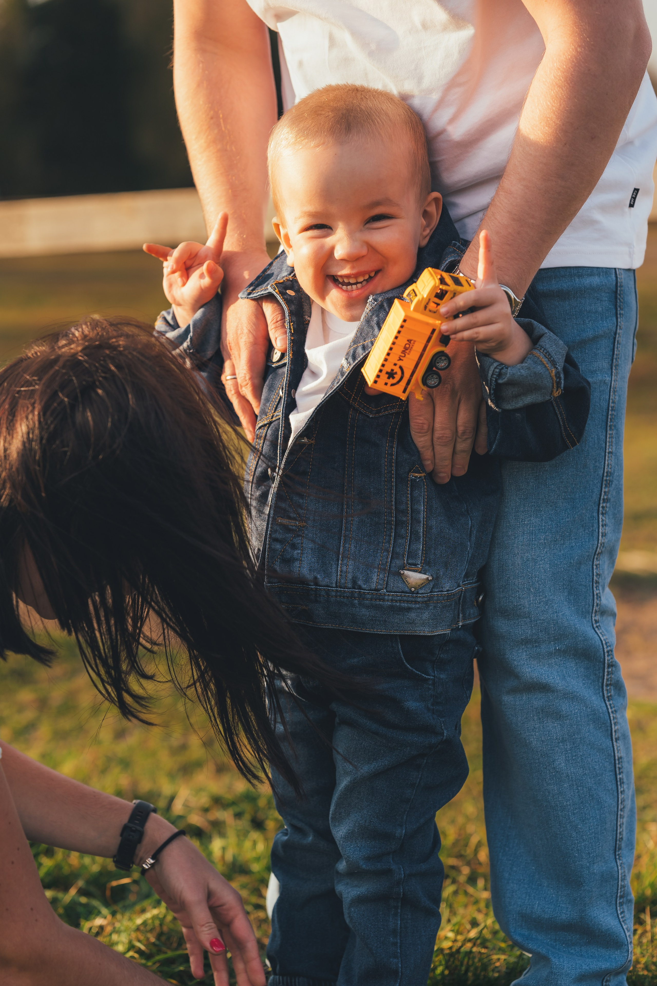 Семья на прогулке в поле, мама надевает кроссовок своему сыну