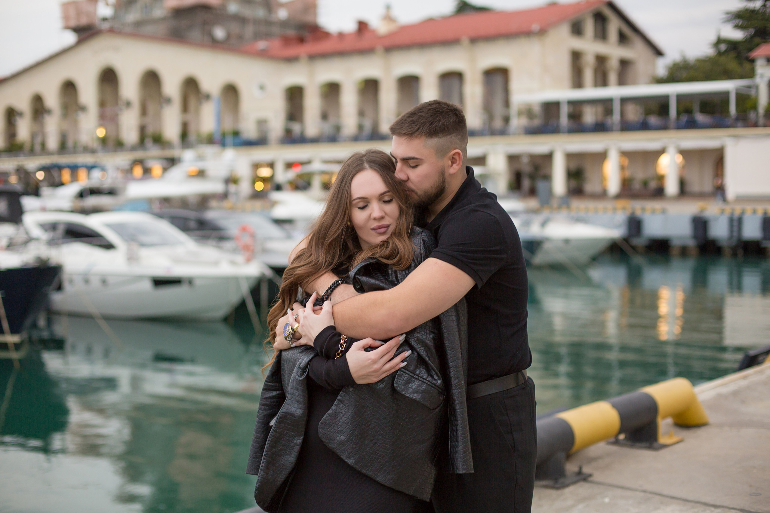 парень накинул девушку курткой и обнял в морском порту