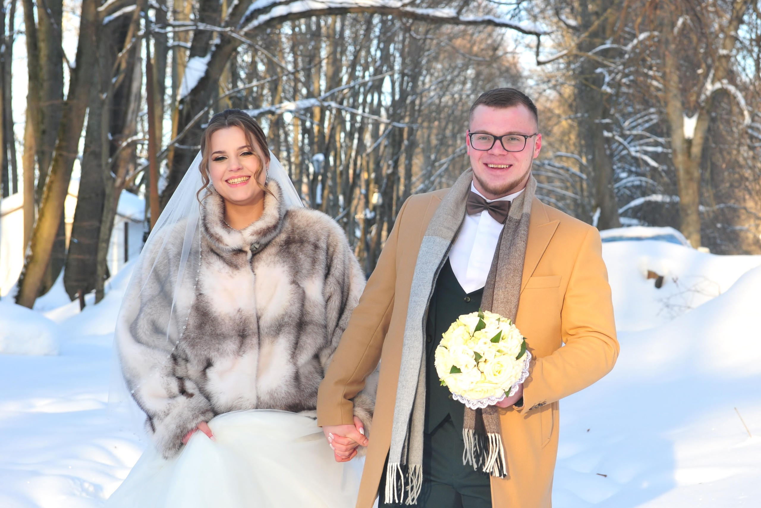 Зимняя свадьба в усадьбе Суханово в сильный мороз на закате, жених и невеста идут среди сугробов и держатся за руки