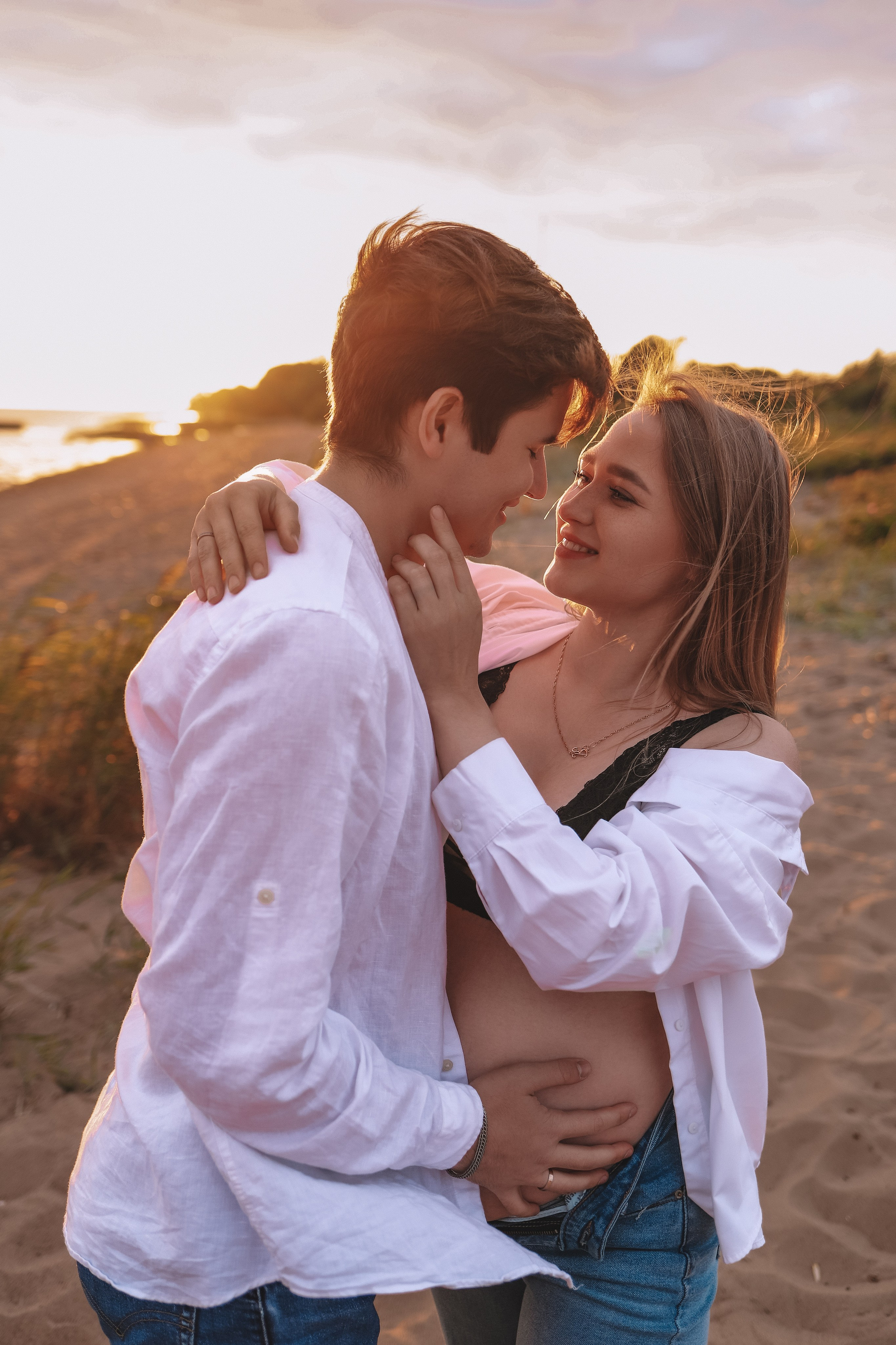 Мужчина обнимает девушку за живот, тёплый свет