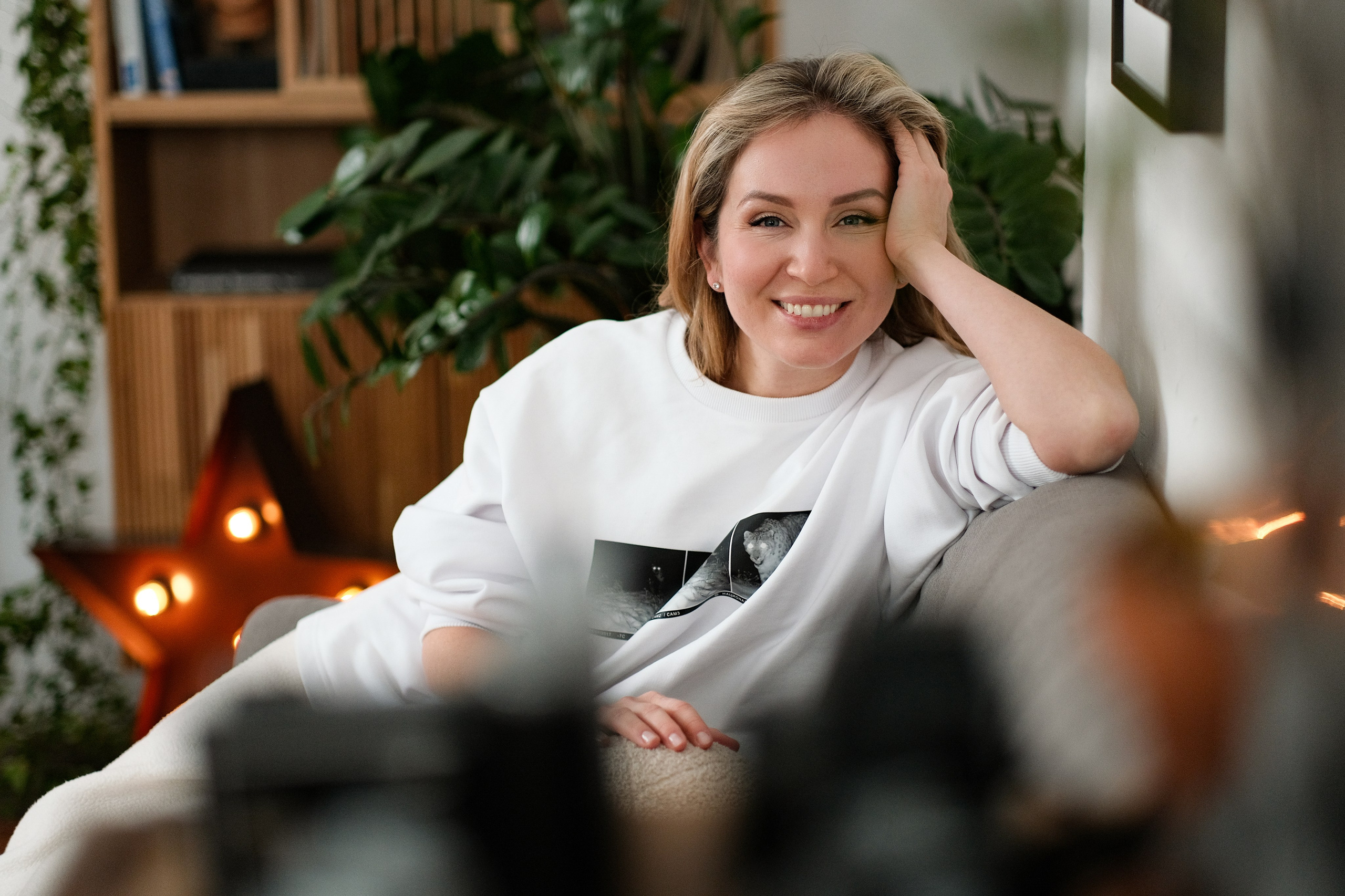 Фото женщины в светлой одежде с поднятой рукой в студии.