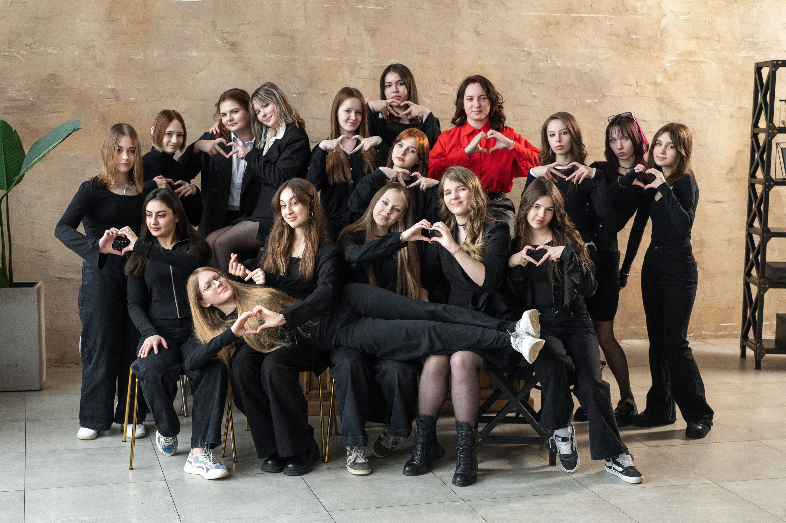 Большая группа старшеклассниц позирует в студии с классным руководителем.