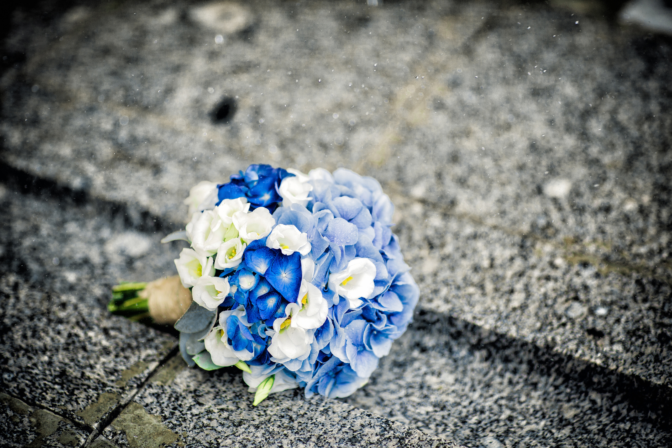 сине-белый букет невесты лежит на граните