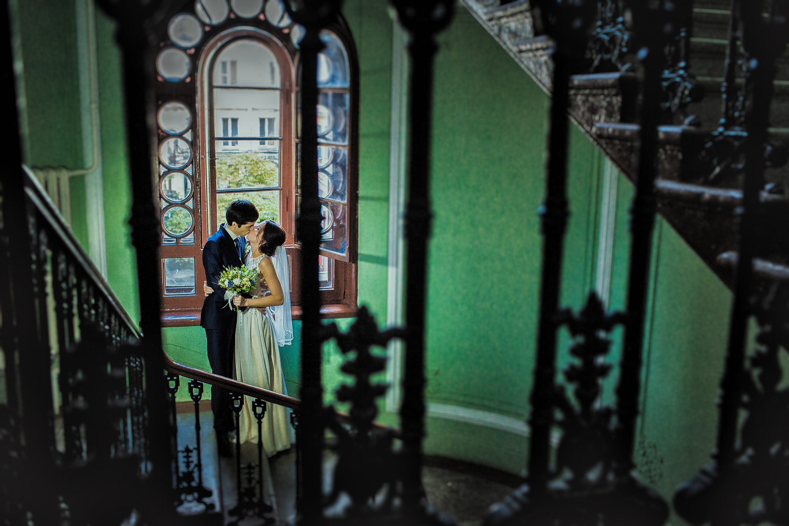 поцелуй около красивого окна в обрамлении старинных лестничных перил